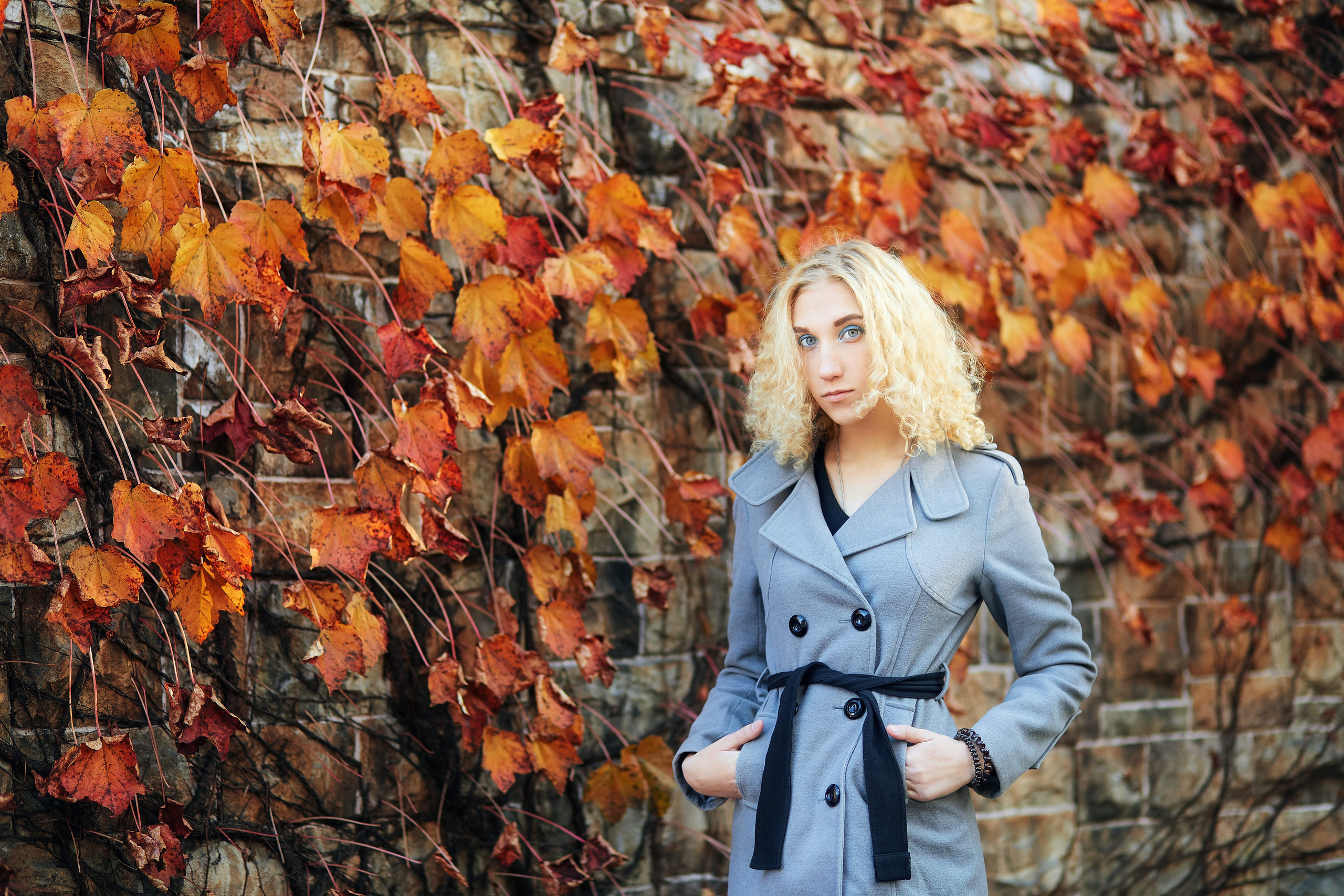 Фотосессия с алыми осенними листьями на стене для блондинки в сером пальто в городе Находке