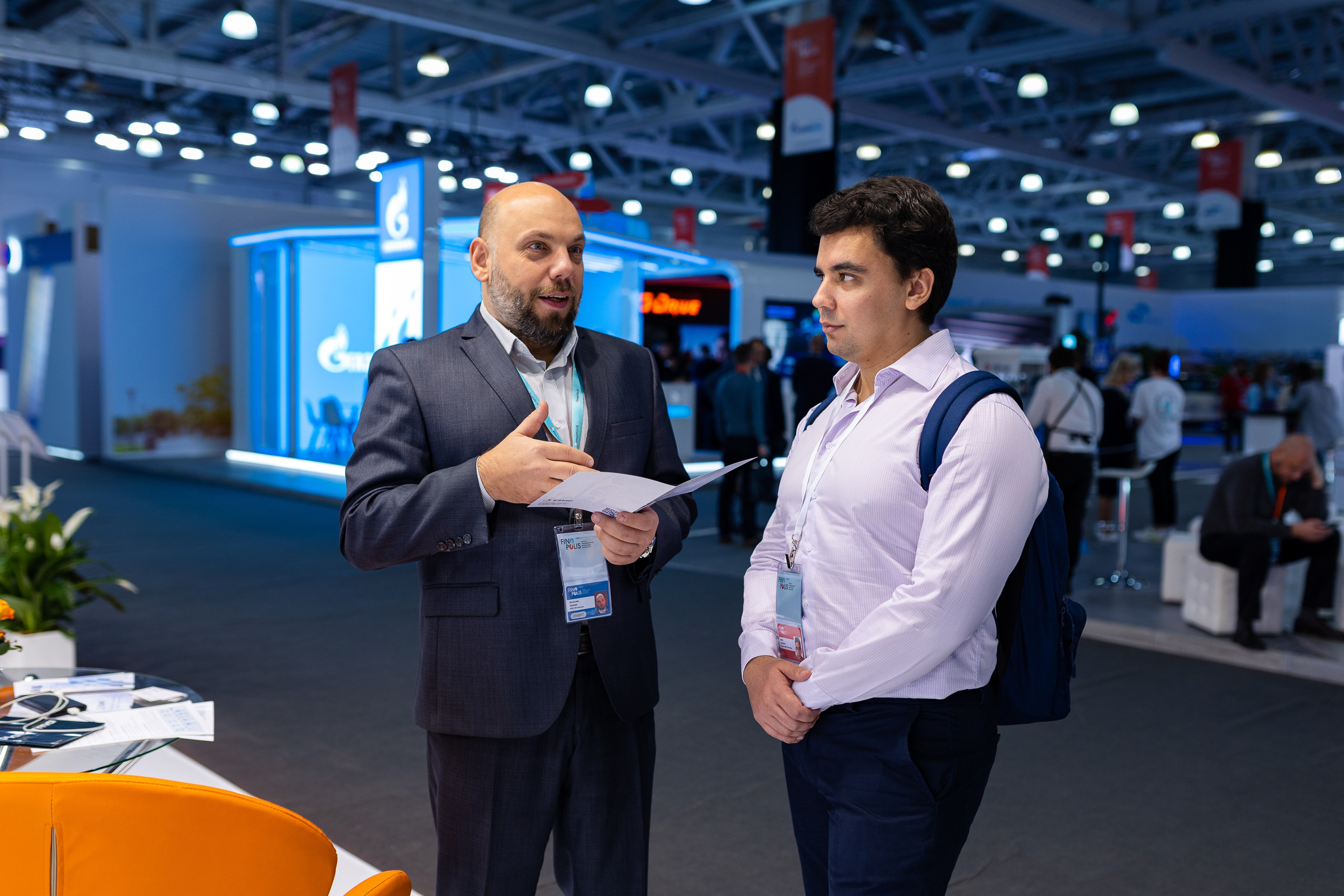 Двое мужчин стоят в выставочном центре один из них объясняет