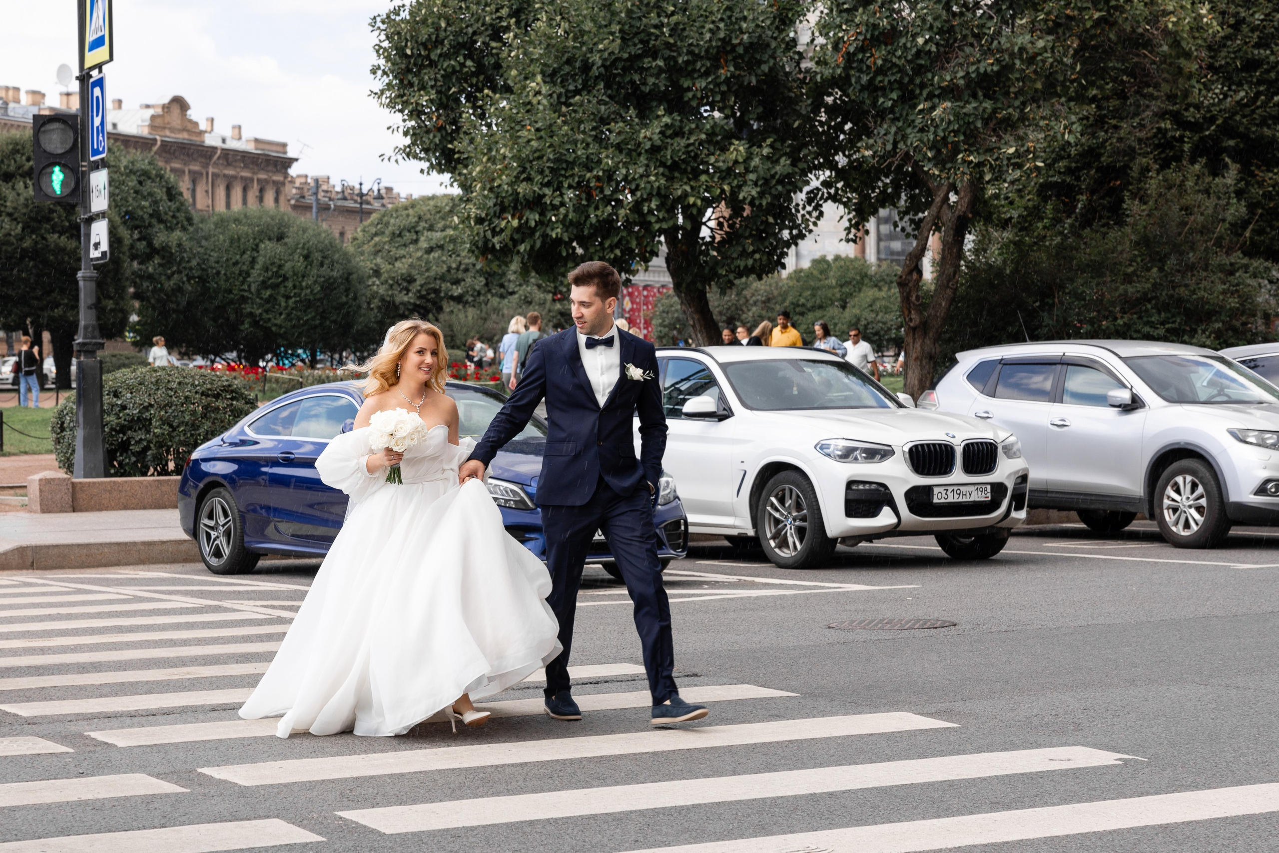 Молодожены переходят дорогу по пешеходному переходу в сторону гостиница Астория
