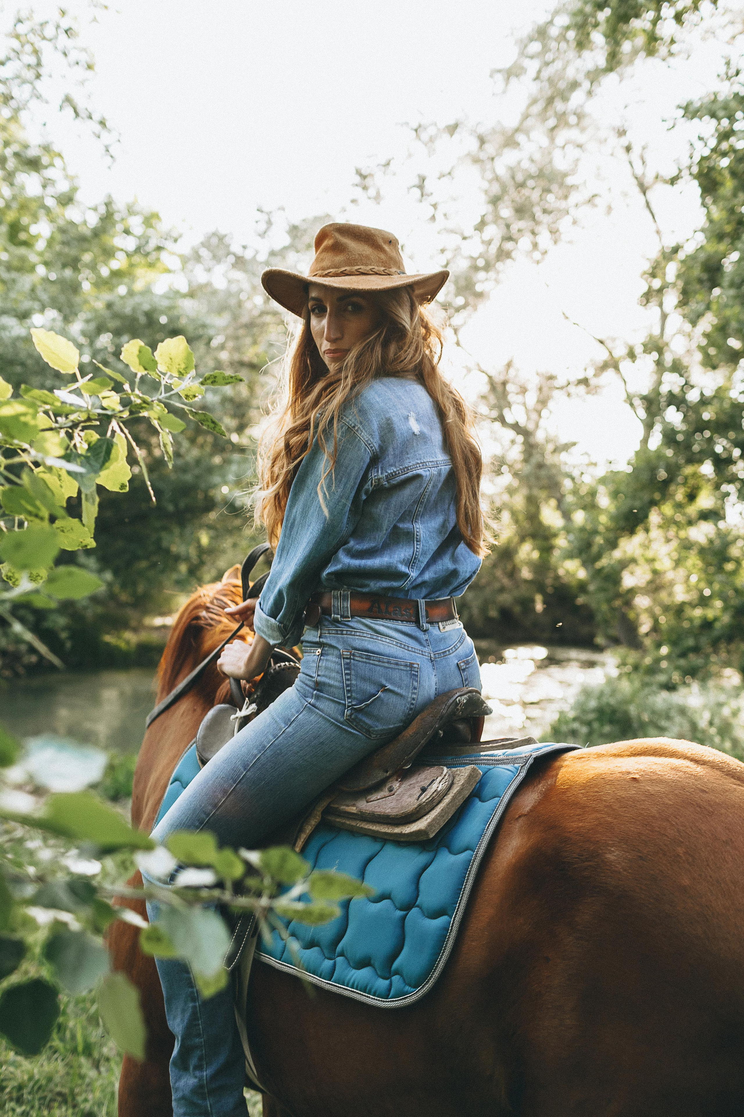 Девушка верхом на лошади в зеленном лесу.