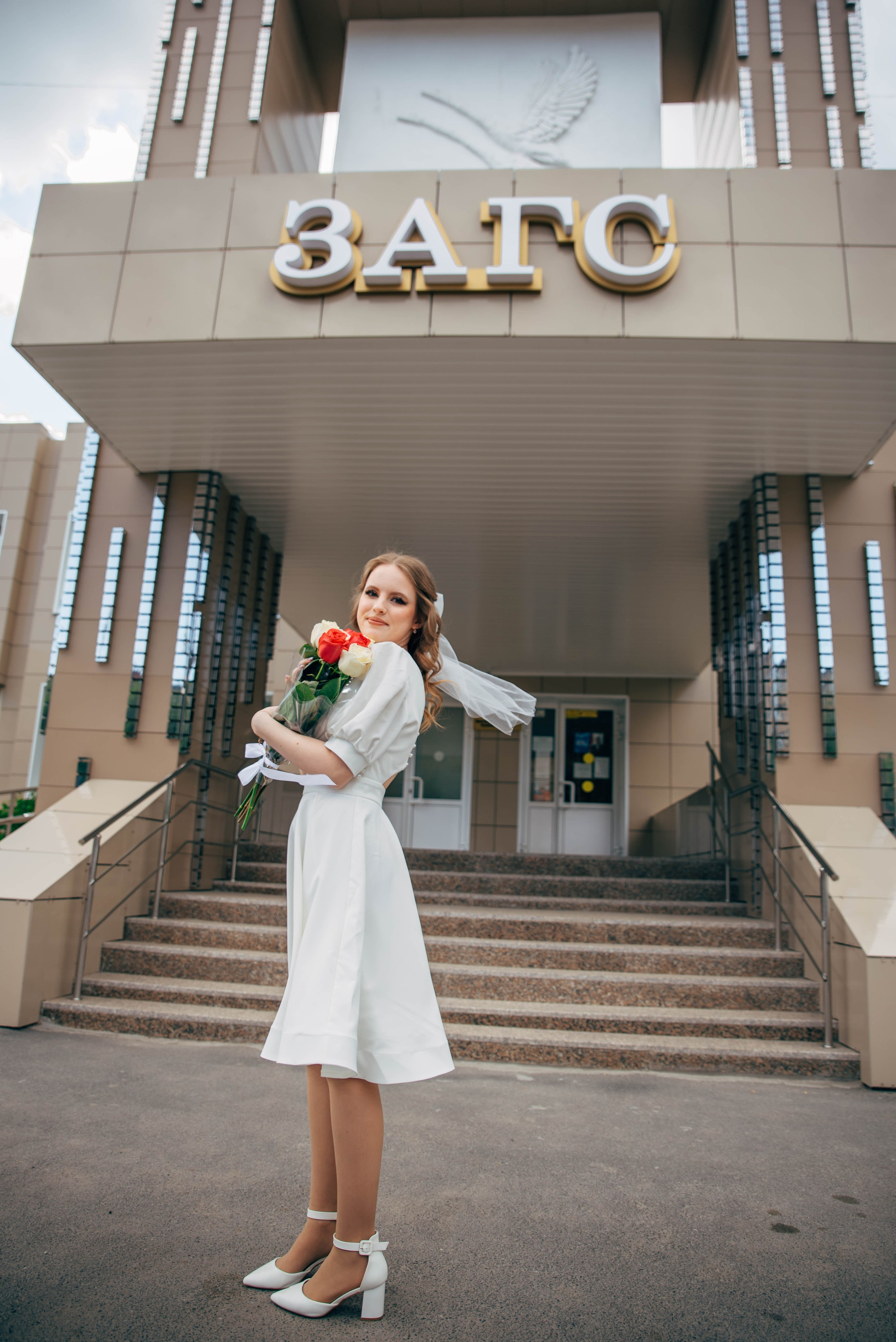 невеста в белом платье с цветами у загса