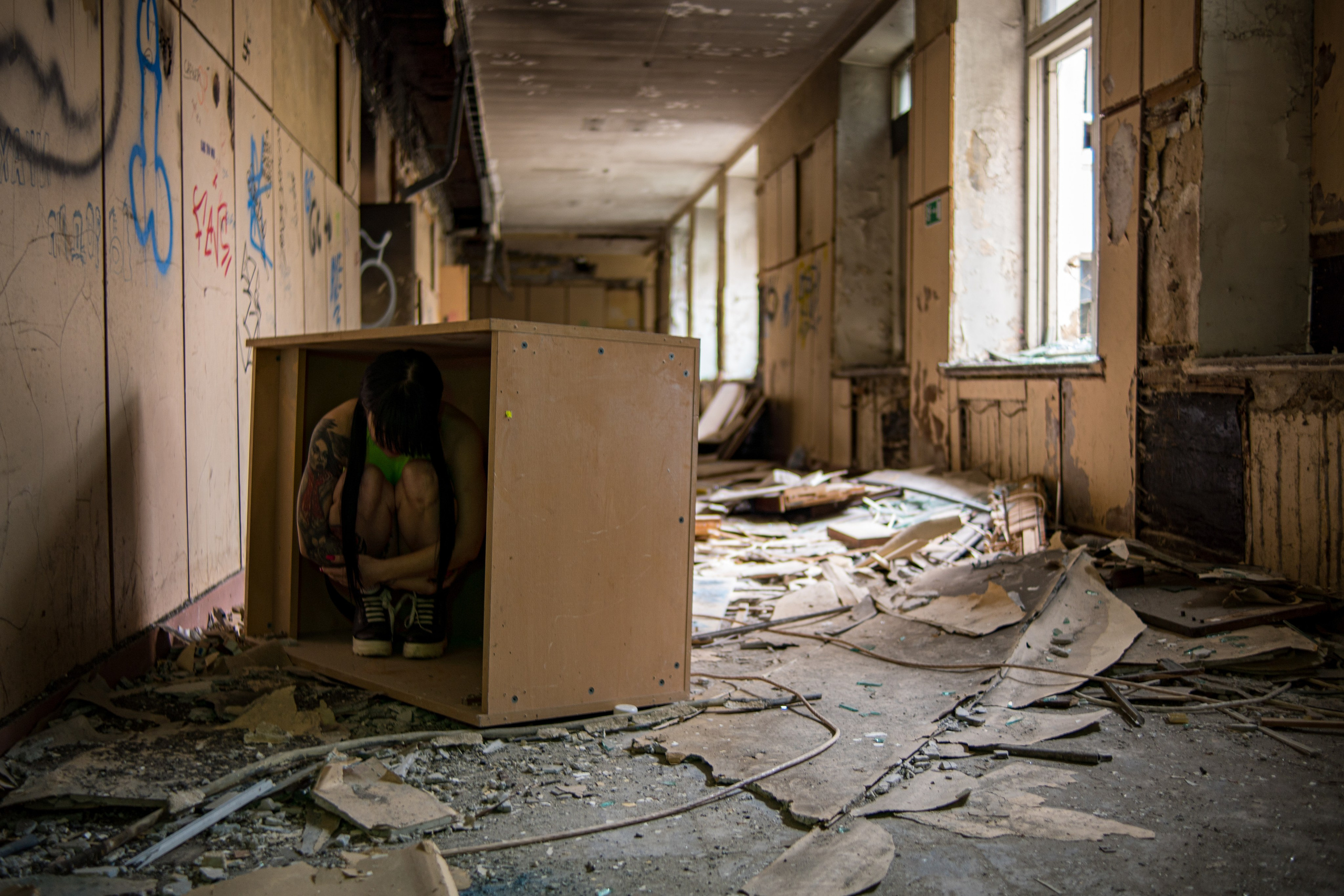 заброшенная школа. посреди коридора лежит ящик в котором сидит девушка