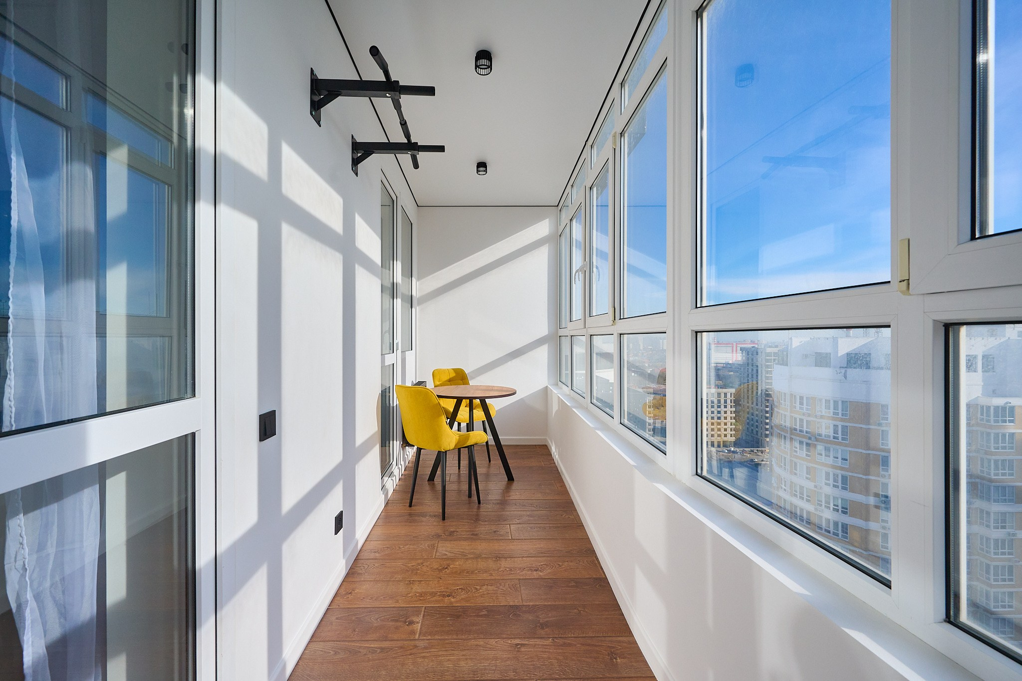 балкон с панорамными окнами желтыми стульями и белые обои 