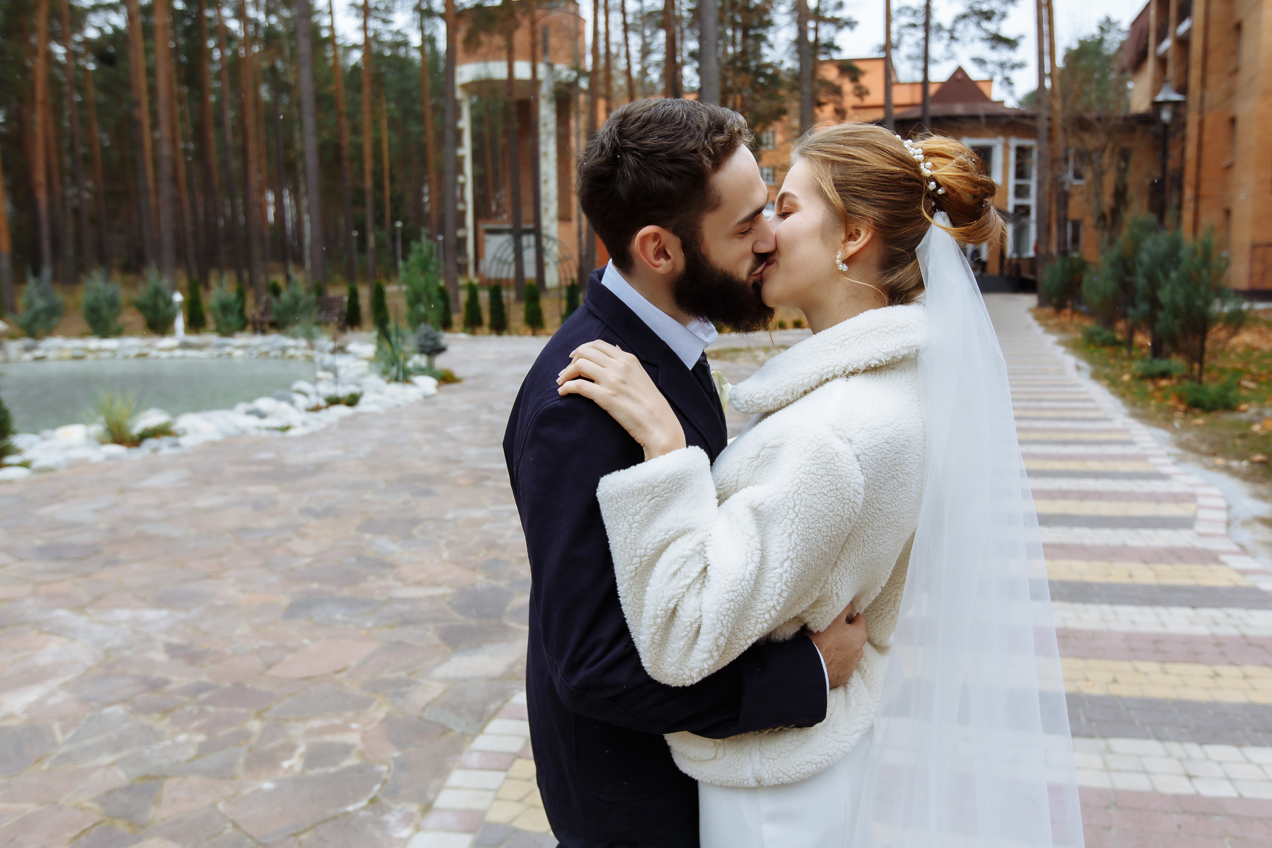 жених целует невесту на фоне каменного здания осенью