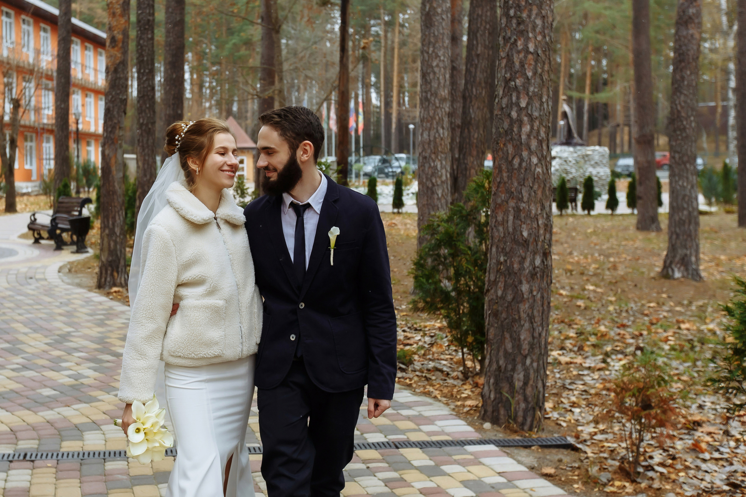 жених с невестой прогуливаются среди деревьев