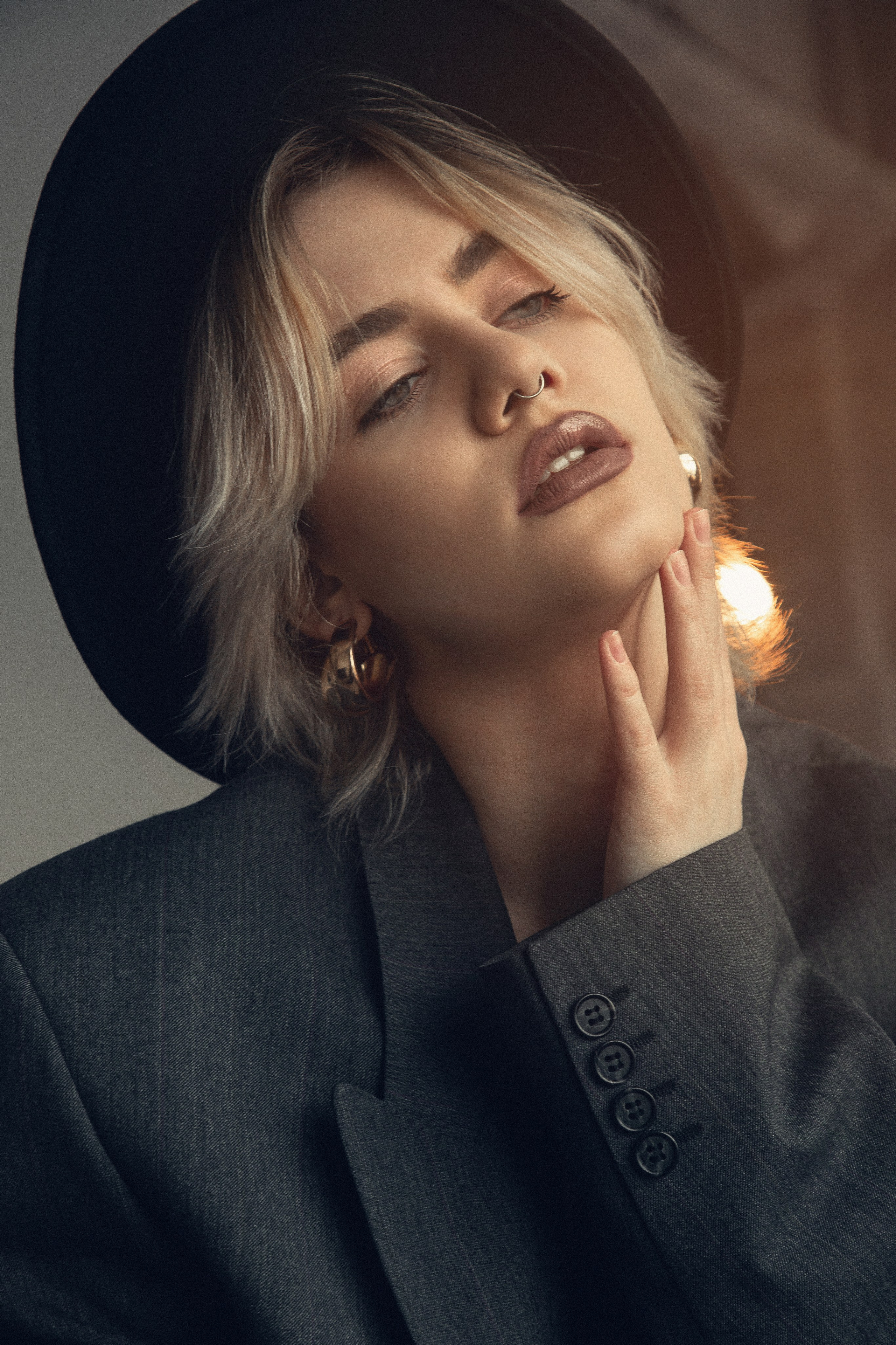 Студийный портрет: женщина в пиджаке и шляпе.