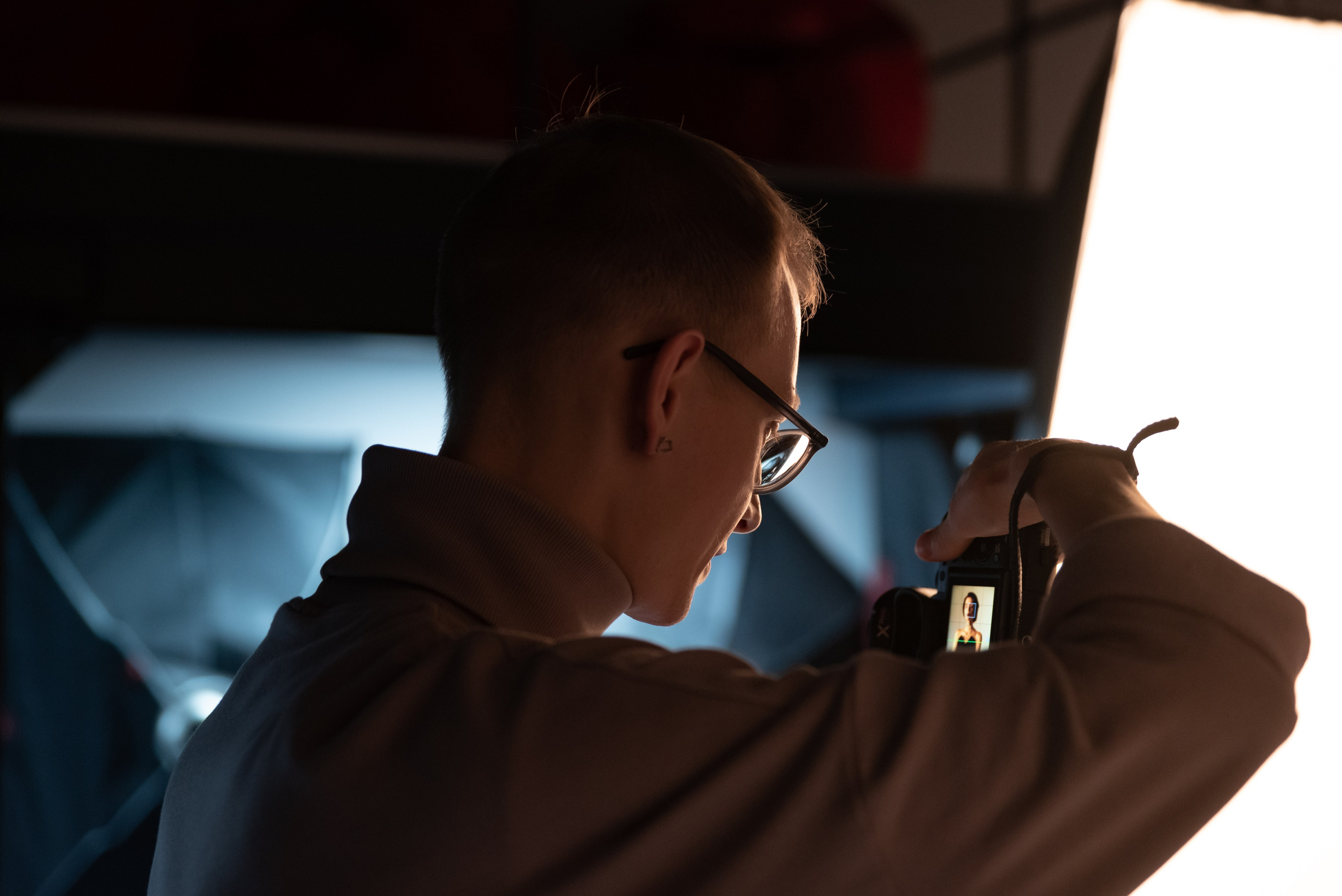 Фотограф стоит спиной, смотрит на изображение на экране камеры.