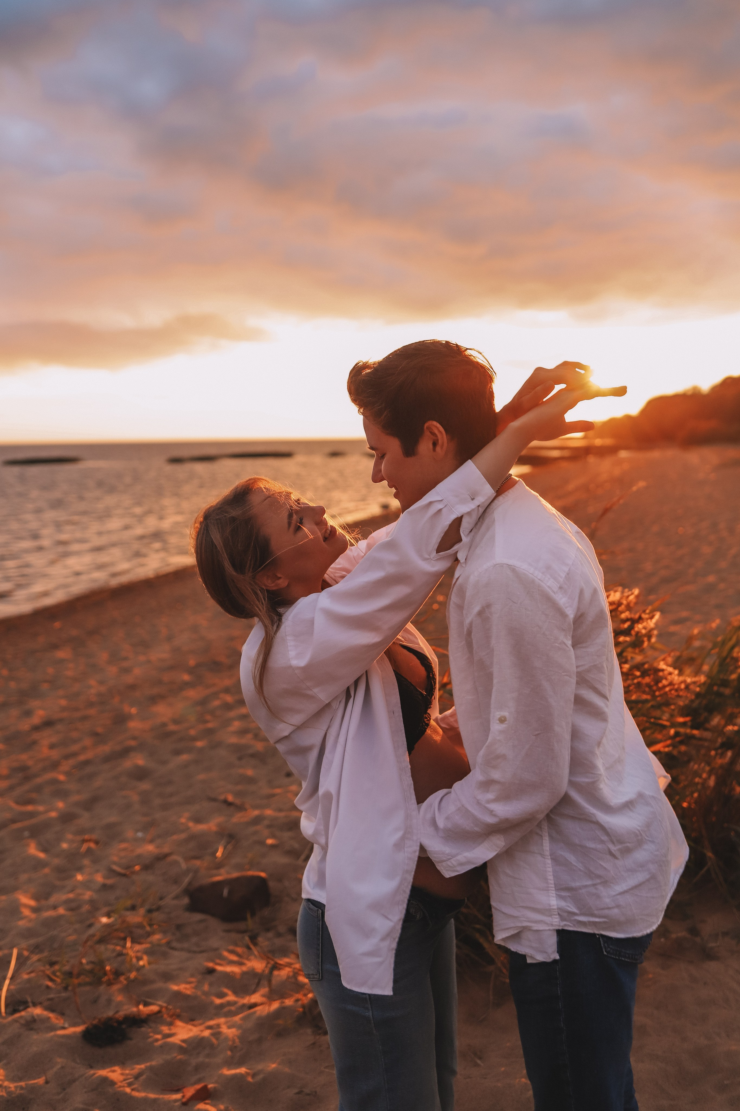 Пара обнимается на фоне заката, тёплые оттенки