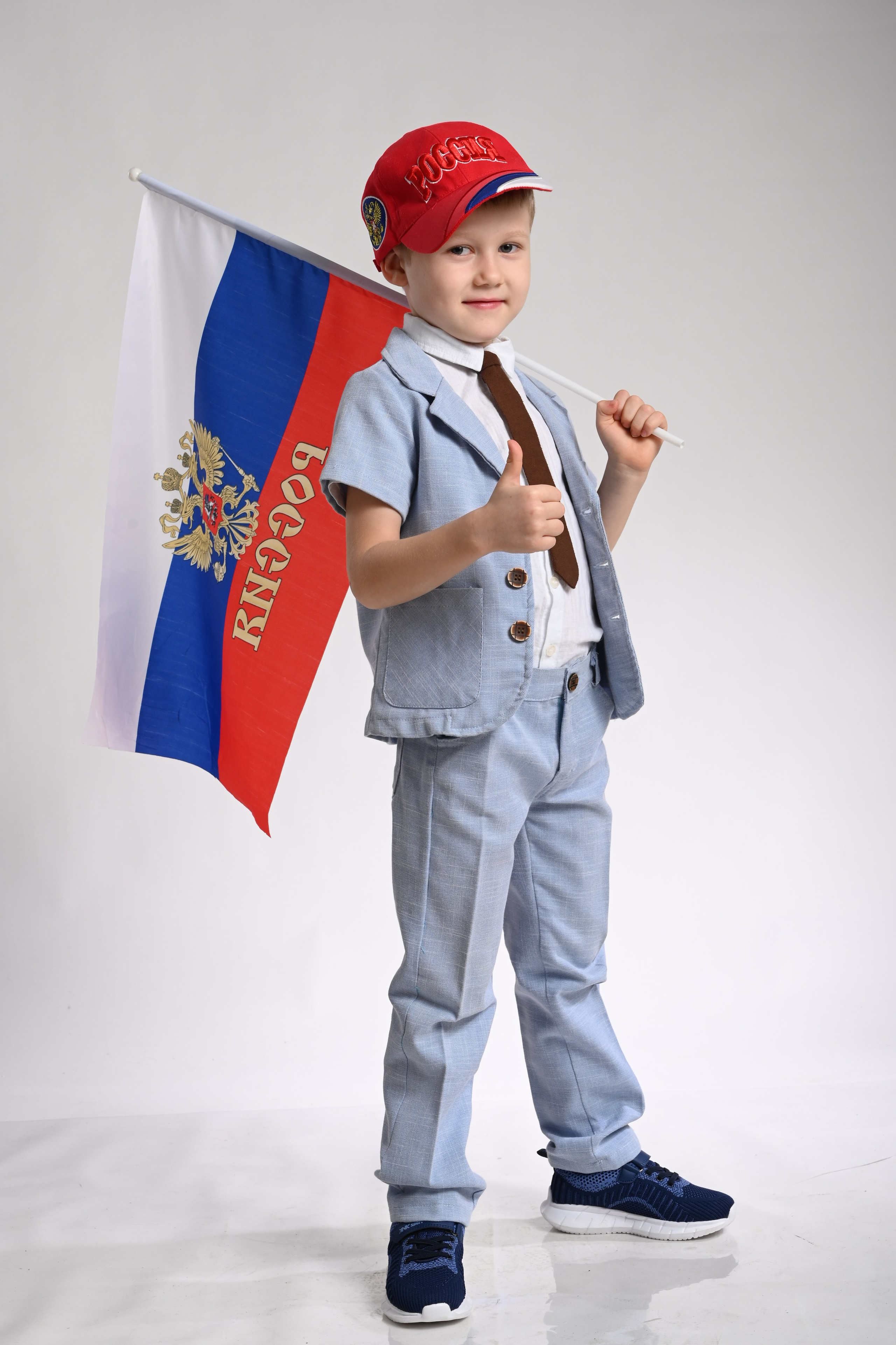 Мальчик выпускник детского сада в Вологде в уличной одежде с флагом улыбается