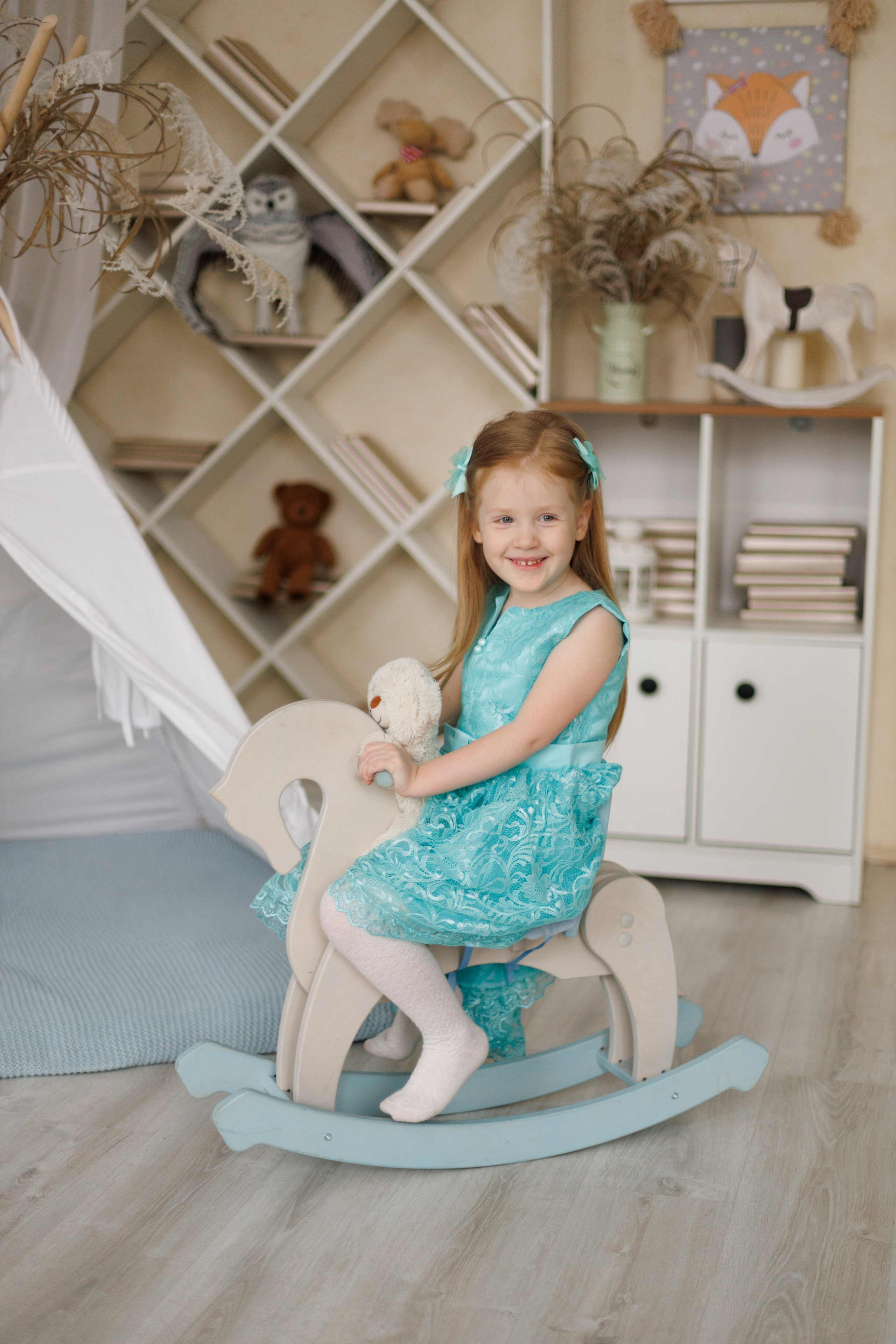 фотография девочки в студии, девочка в голубом платье, девочка качается на лошадке