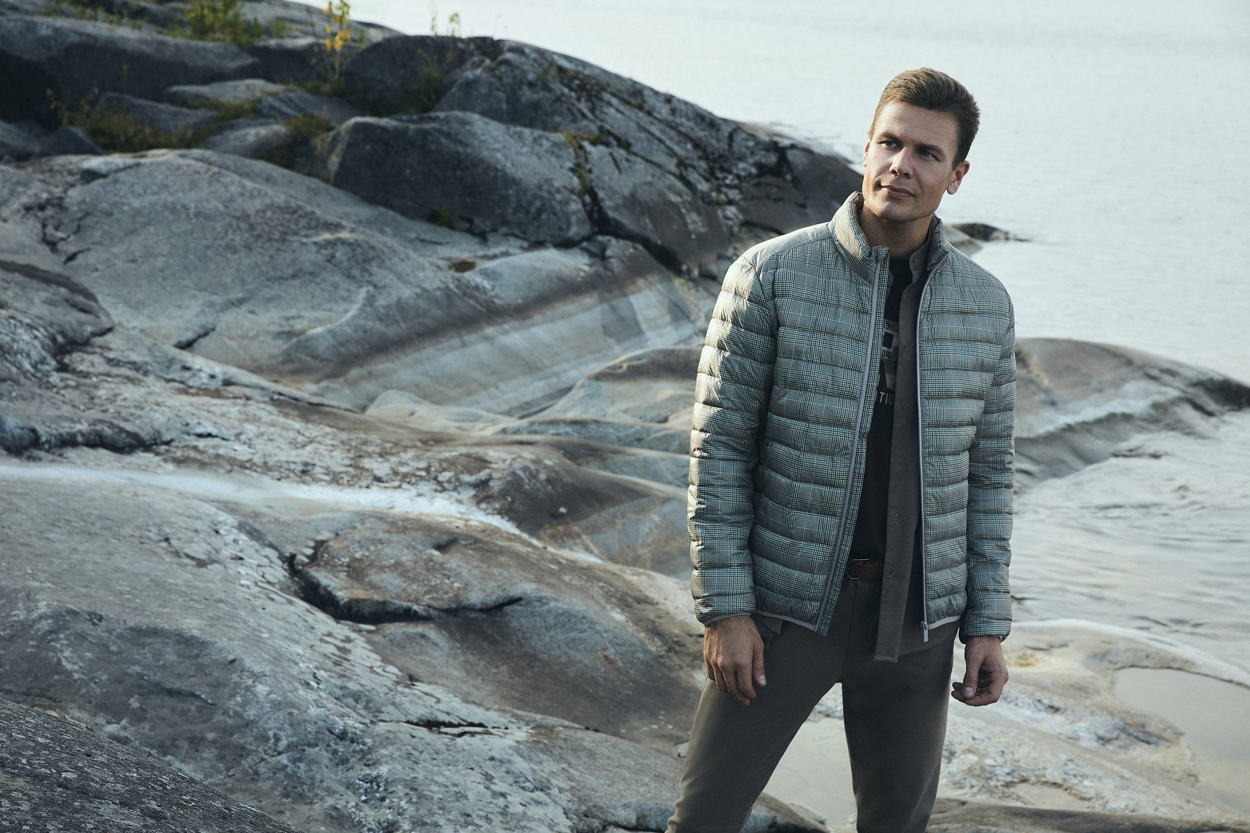 Мужчина модель в стеганой куртке на берегу