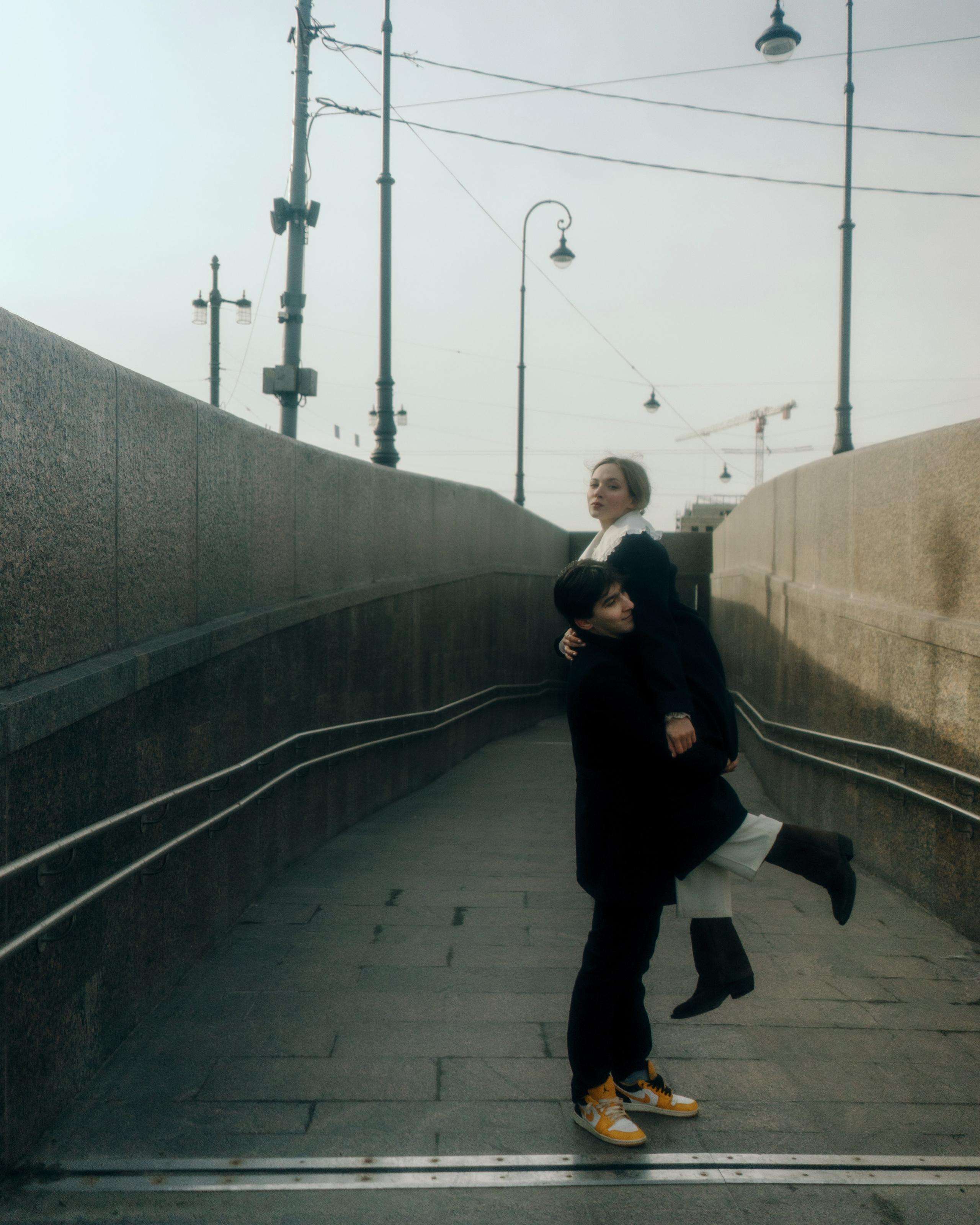 Фотосессия пары на набережной, девушка на руках у мужчины, авторская love story съемка в Петербурге с атмосферой кино и свободы