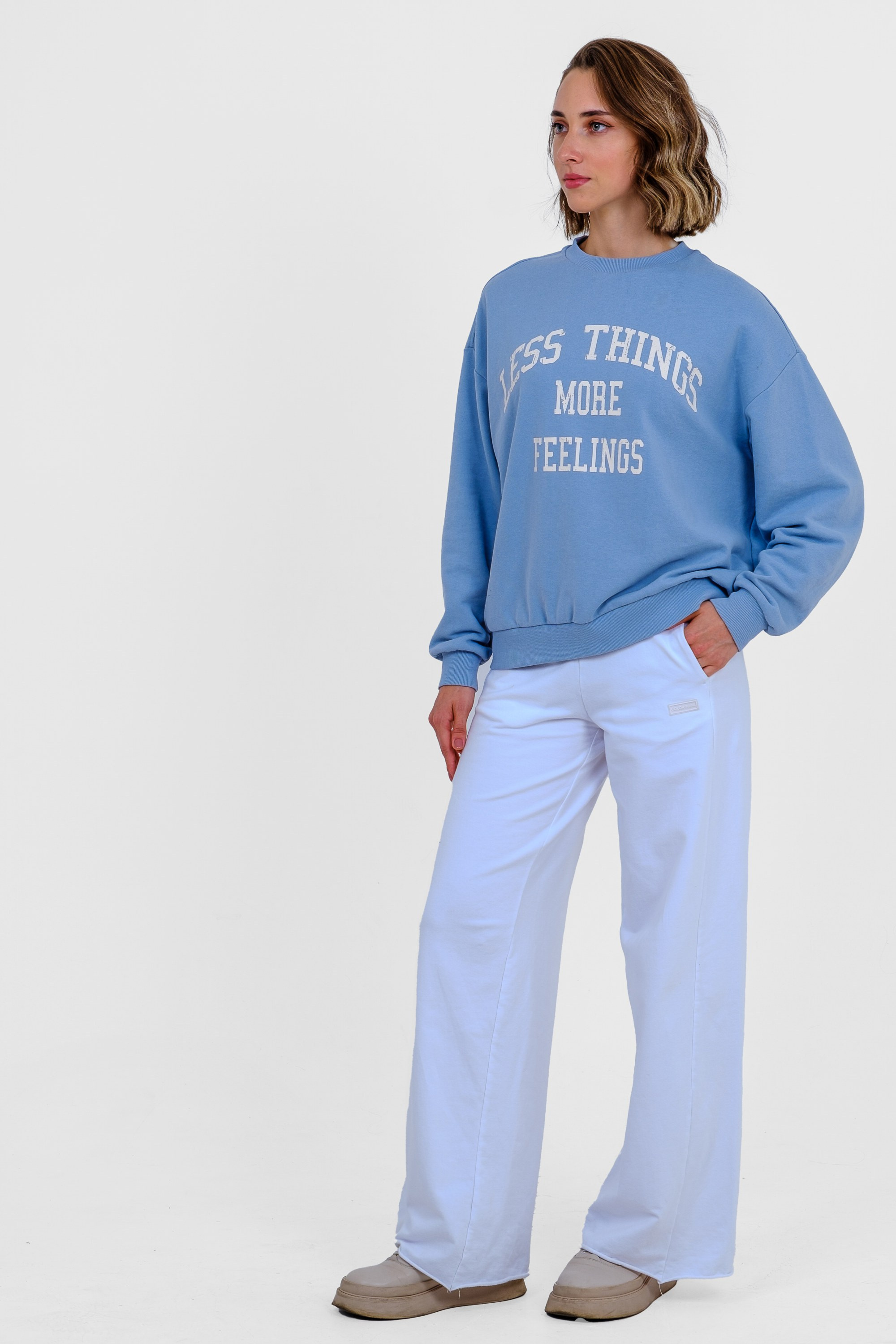 Девушка в голубом свитшоте с принтом, голубых спортивных брюках и кроссовках. Фото для маркетплейсов