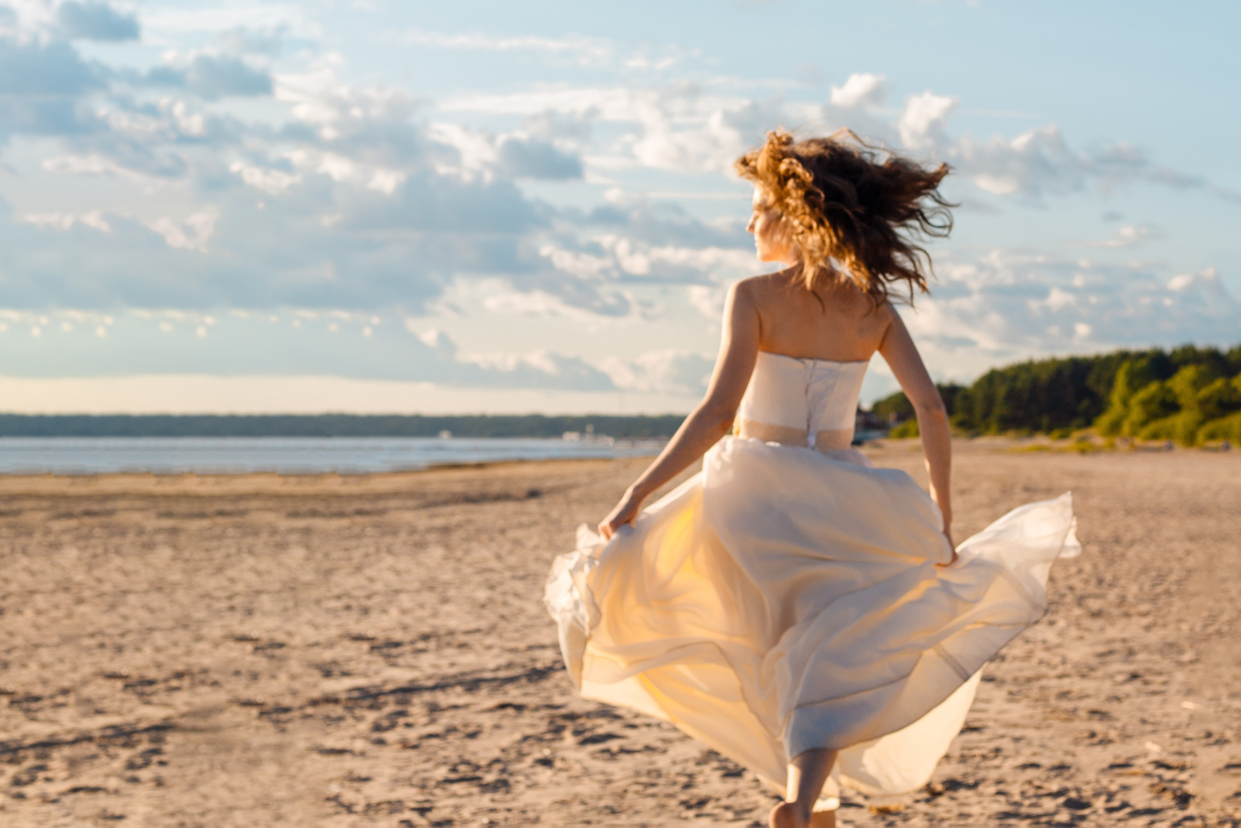 Девушка бежит по берегу залива. Лучи солнца. Девушка с развивающимися волосами на ветру. Девушка в лучах. Воздушное платье.