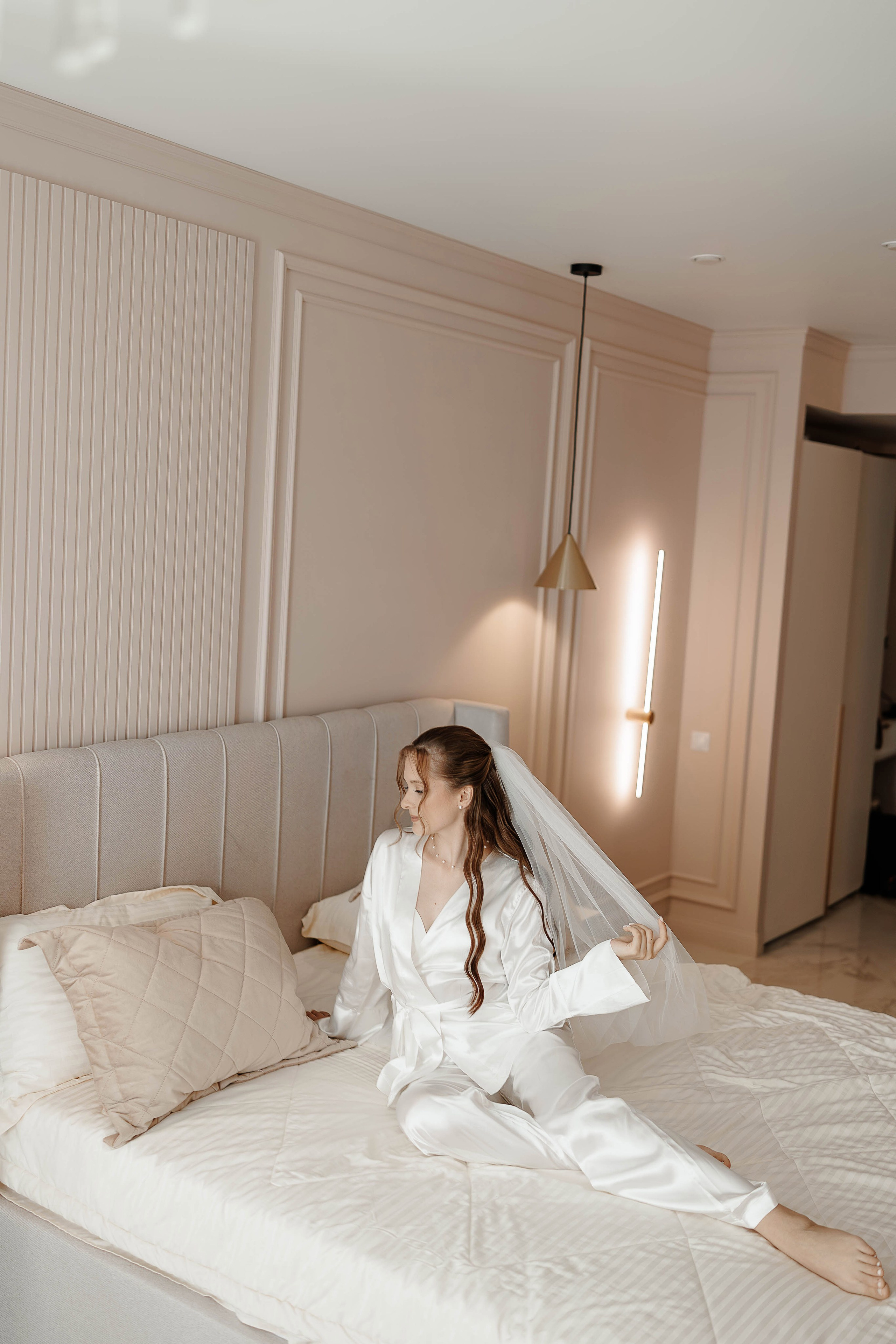 Невеста утром на сборах лежит на кровати в отеле Свадебная фотосессия в отеле