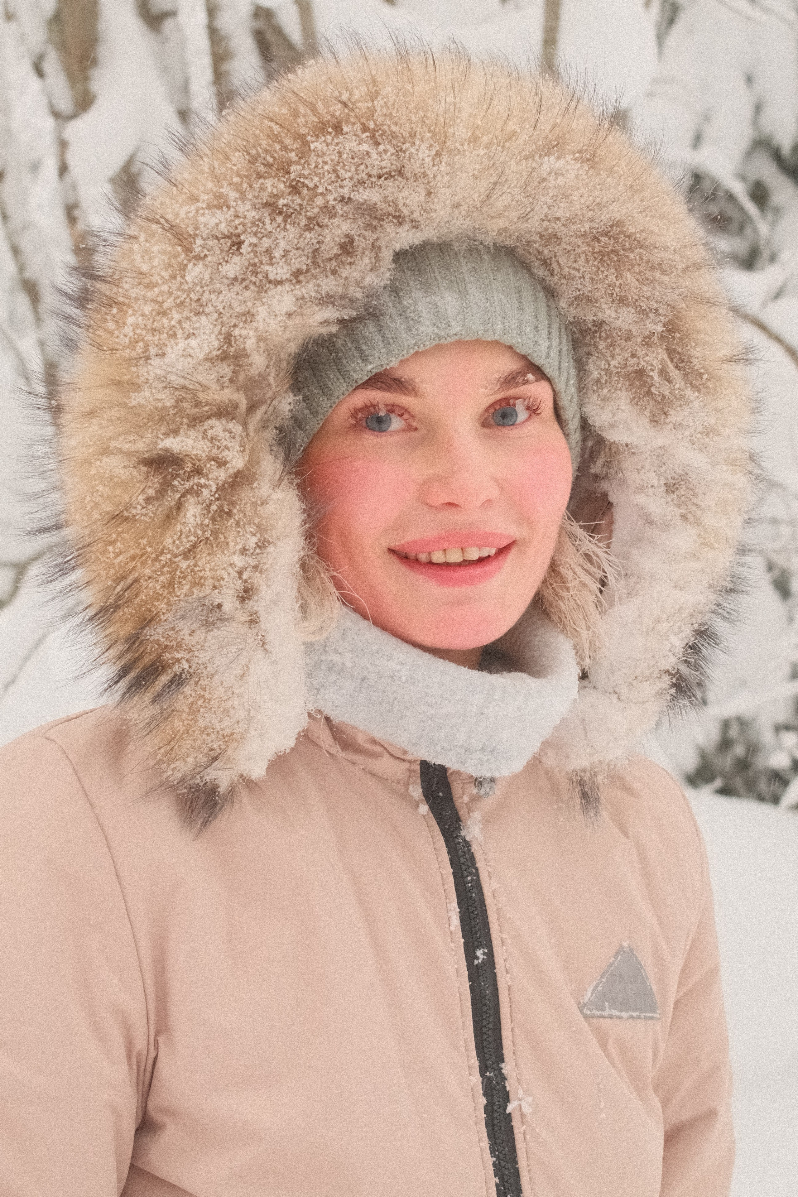 Портрет девушки в зимней одежде с меховым капюшоном в зимнем лесу