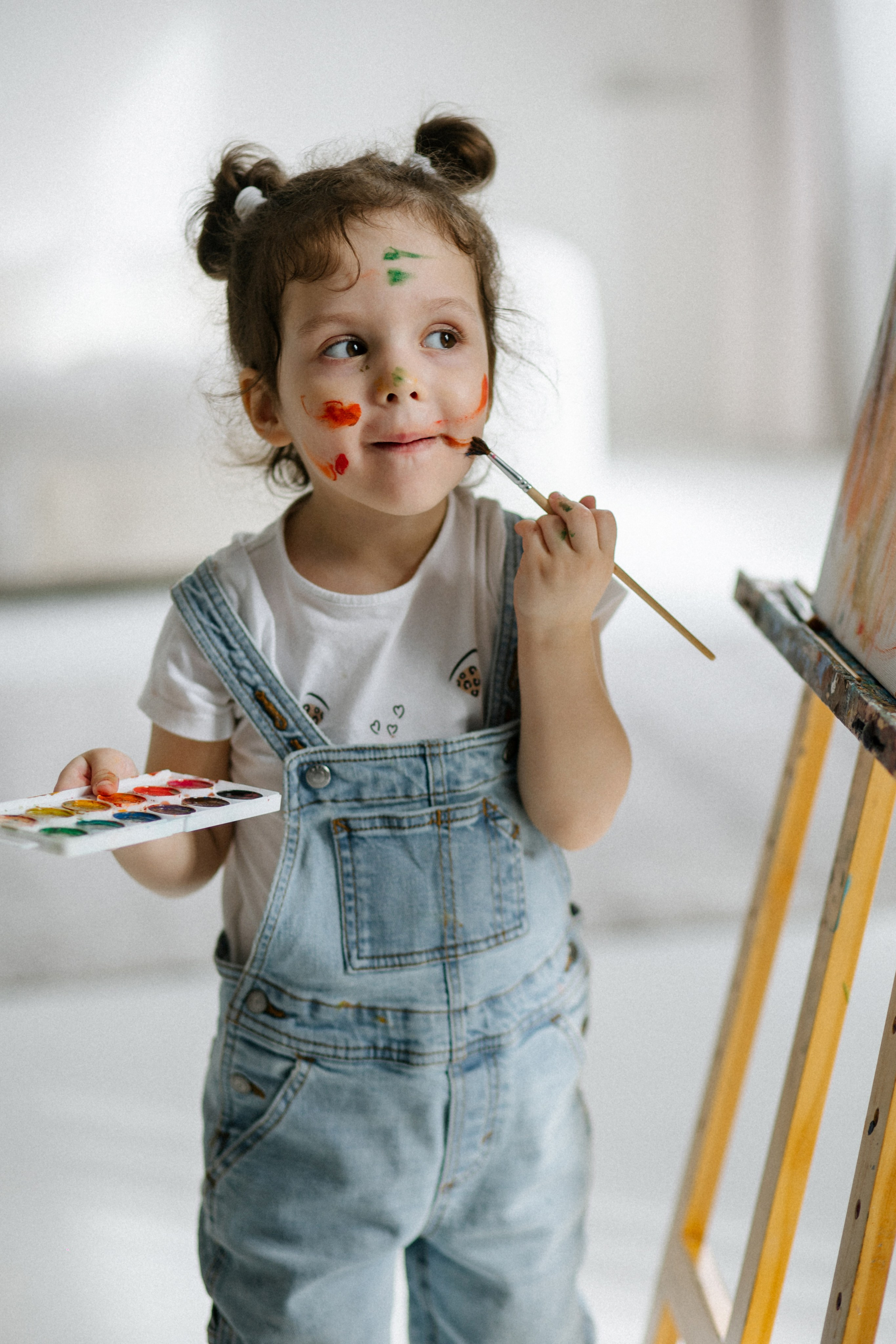 Дурачество с красками: сестрички рисуют на лице друг друга у мольберта. Семейная фотосессия в студии Архангельска