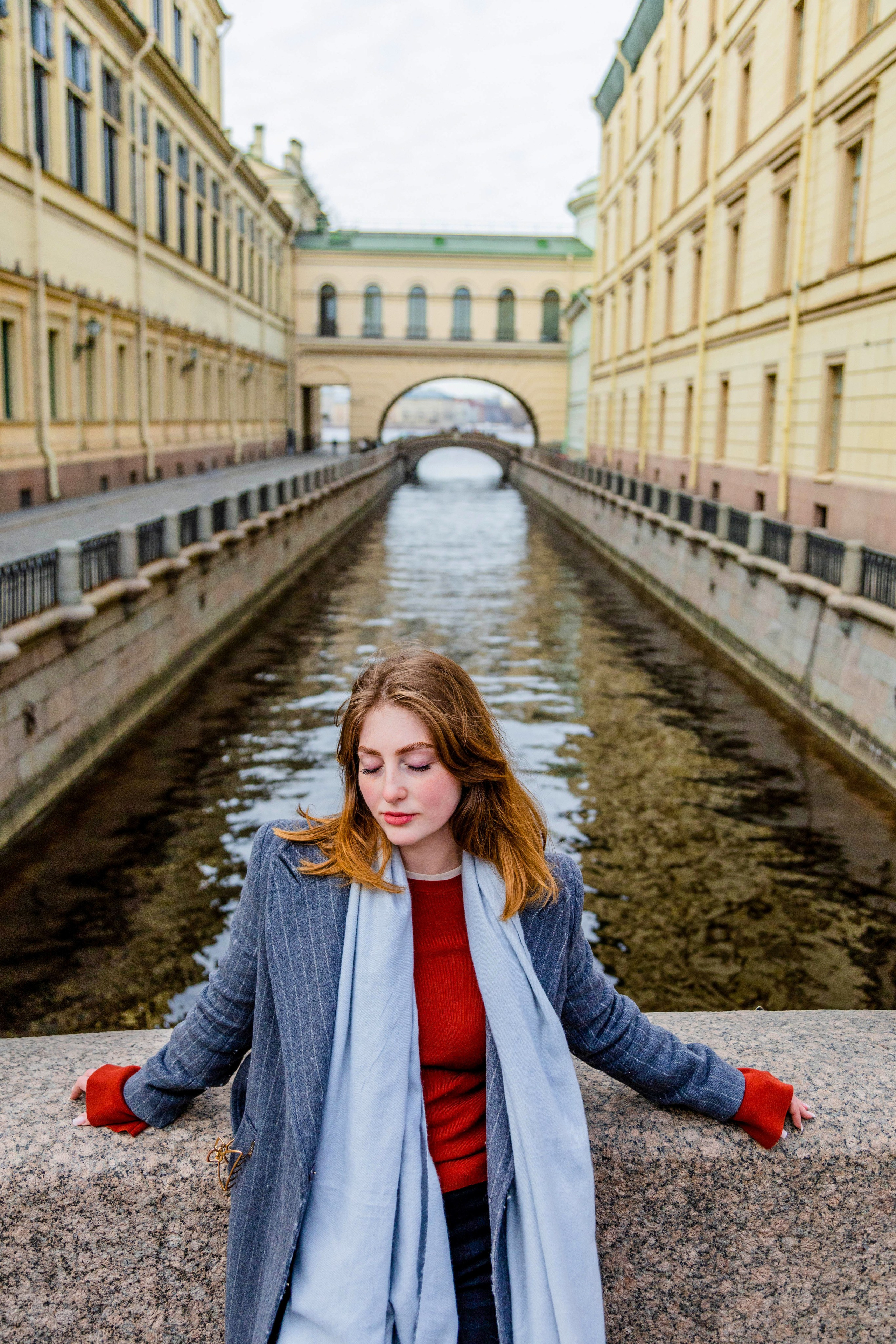 Съёмка на Эрмитажном мостике  в Петербурге, девушка стоит с закрытыми глазами, на заднем плане панорама Невы 