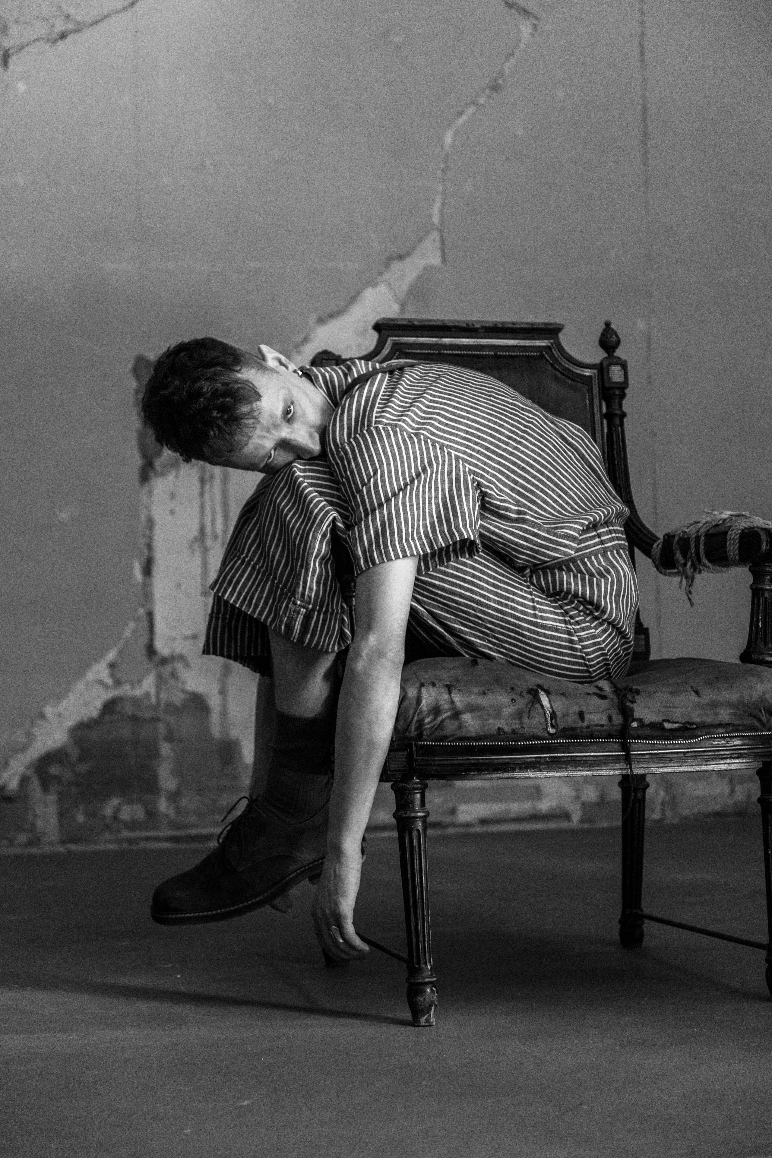 Стильная мужская фотосессия в студии СПб, мужчина сидит на стуле в минималистичном образе.