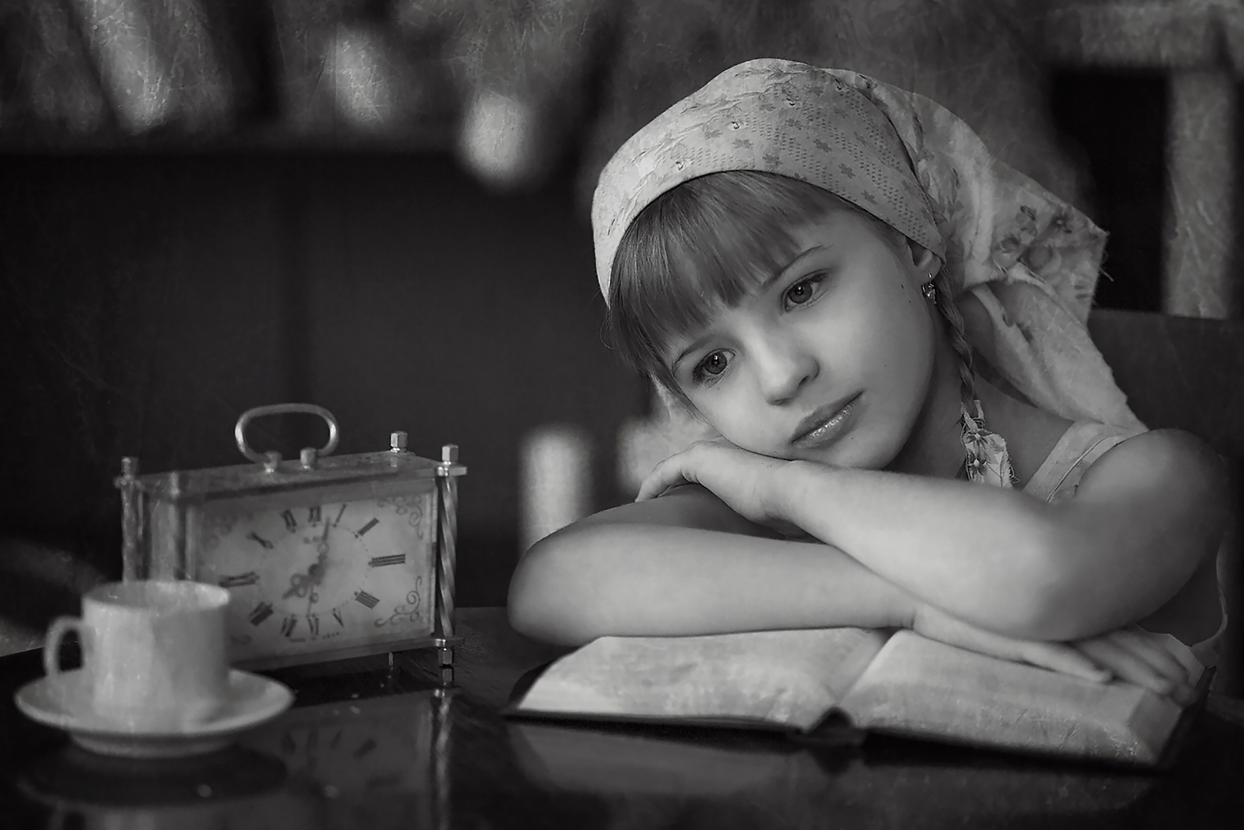 Грустная девочка в платке за столом и книгой грустит. Красивая. Магия чёрно-белой фотографии.