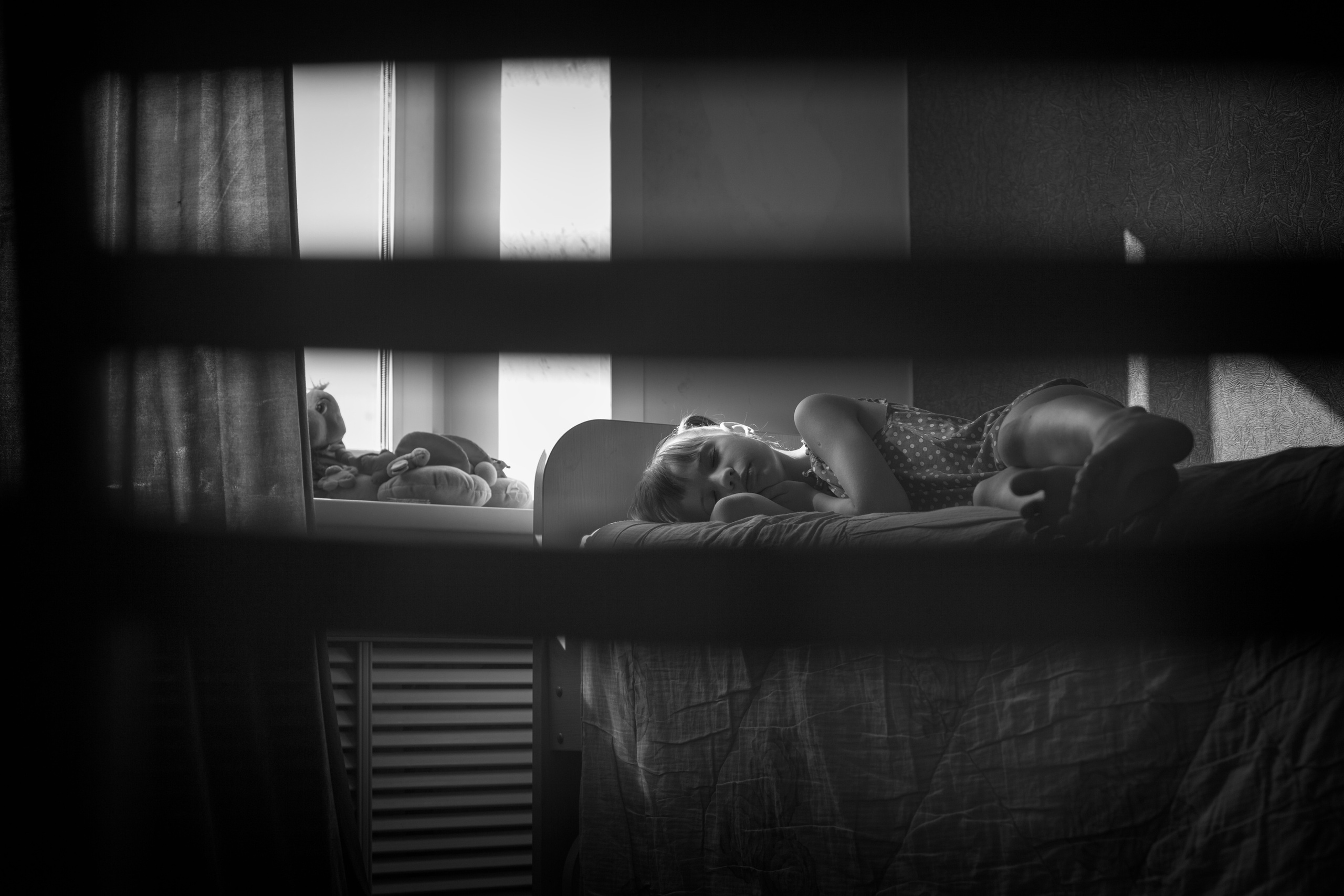 Девочка спи на кровати у окна и за ней подглядывает мама.