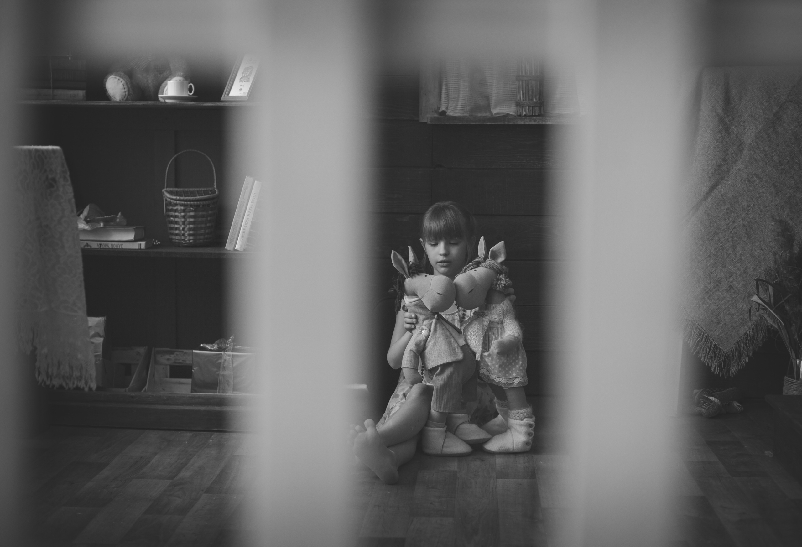 Девочка играет с игрушками -лошадками в своей комнате, уединившись от сестры.