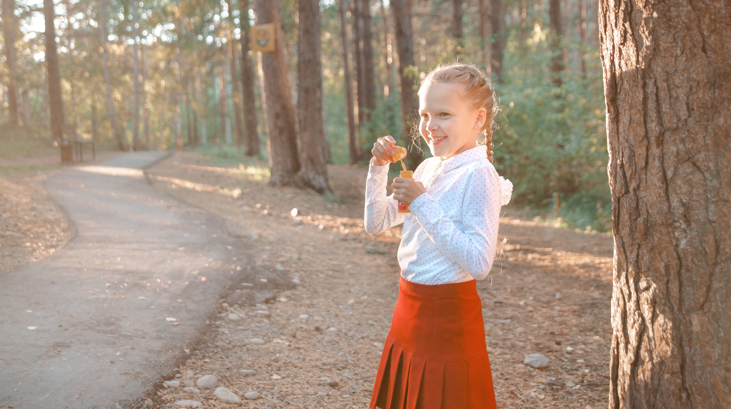 Детская фотосессия осенью - школьница стоя дует мыльные пузыри