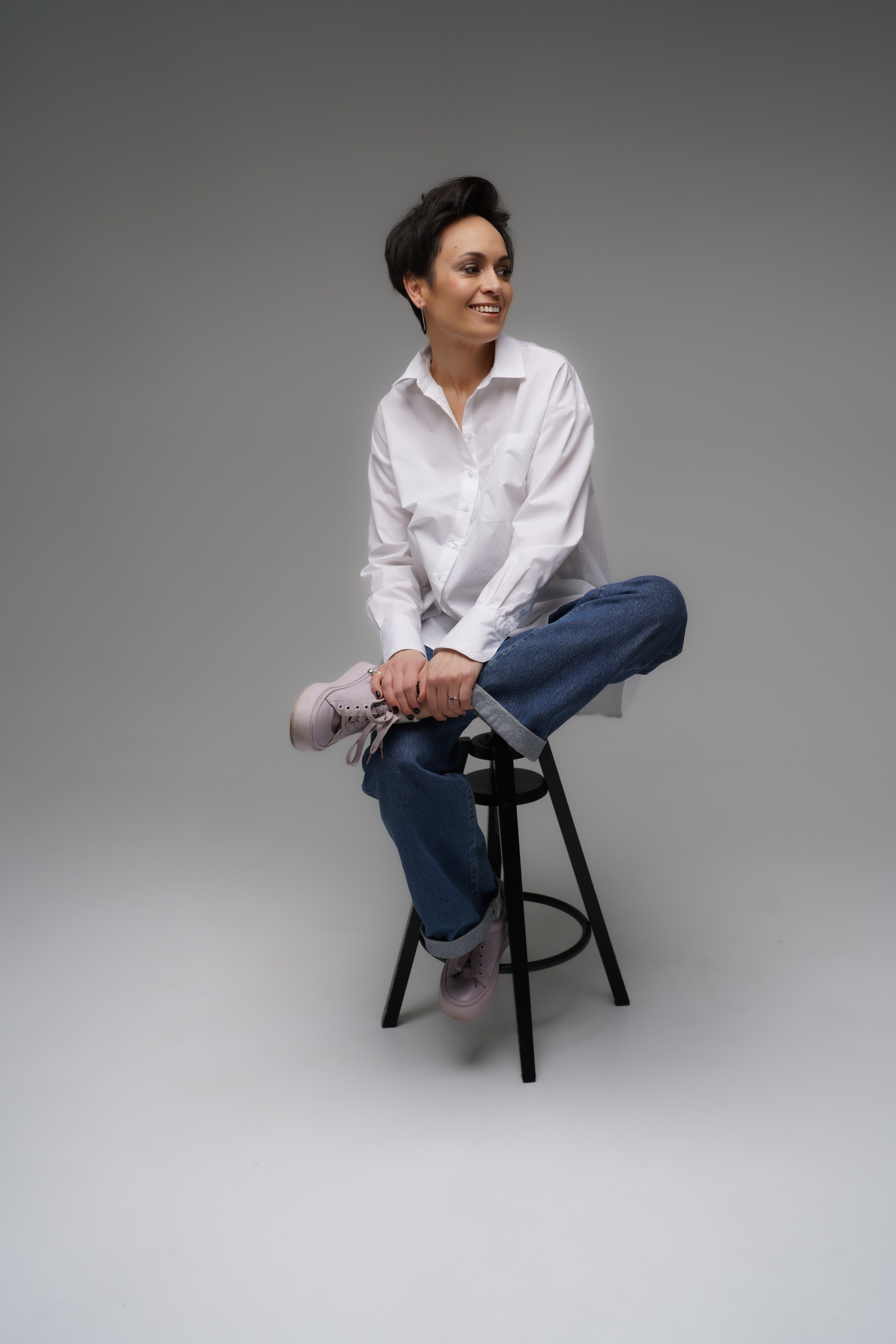 Девушка позирует в фотостудии сидя на стуле