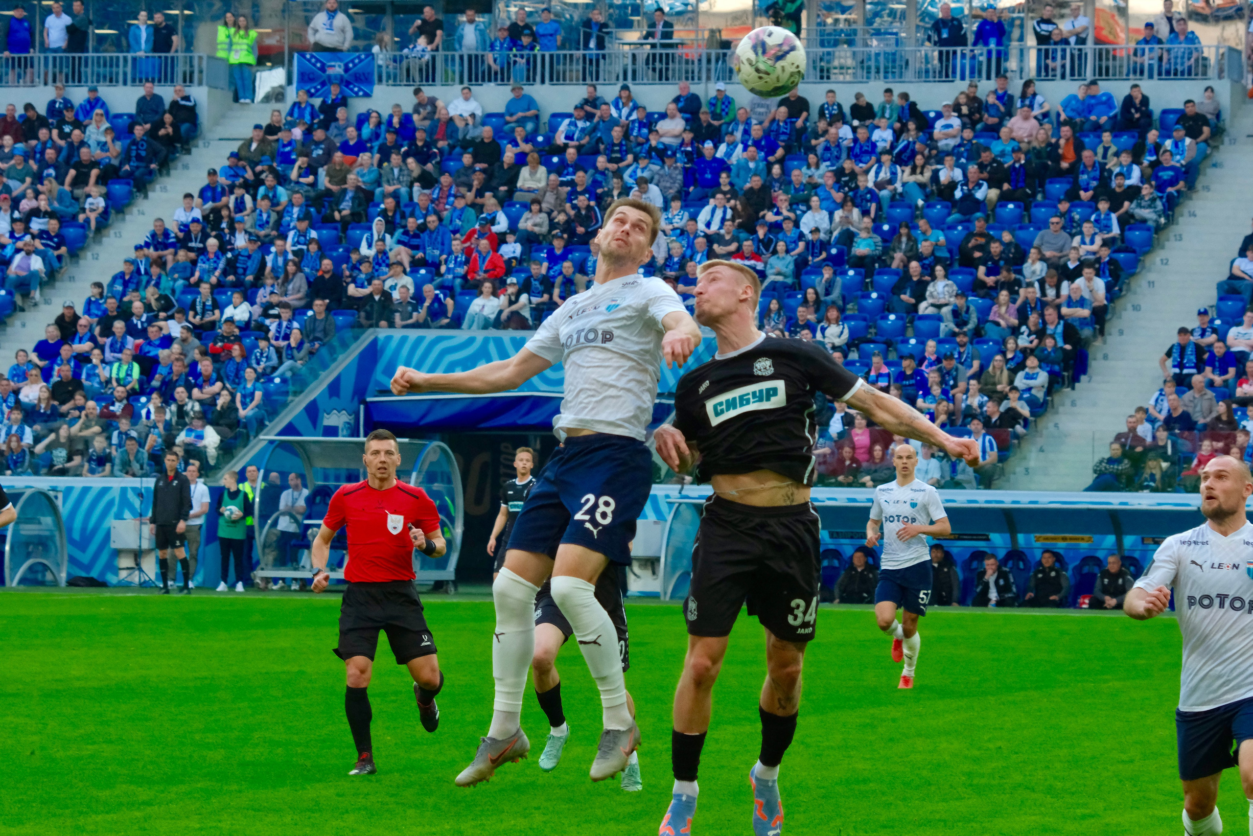 Футболист в красной форме выполняет навес с фланга на стадионе «Волгоград Арена» во время матча первенства области