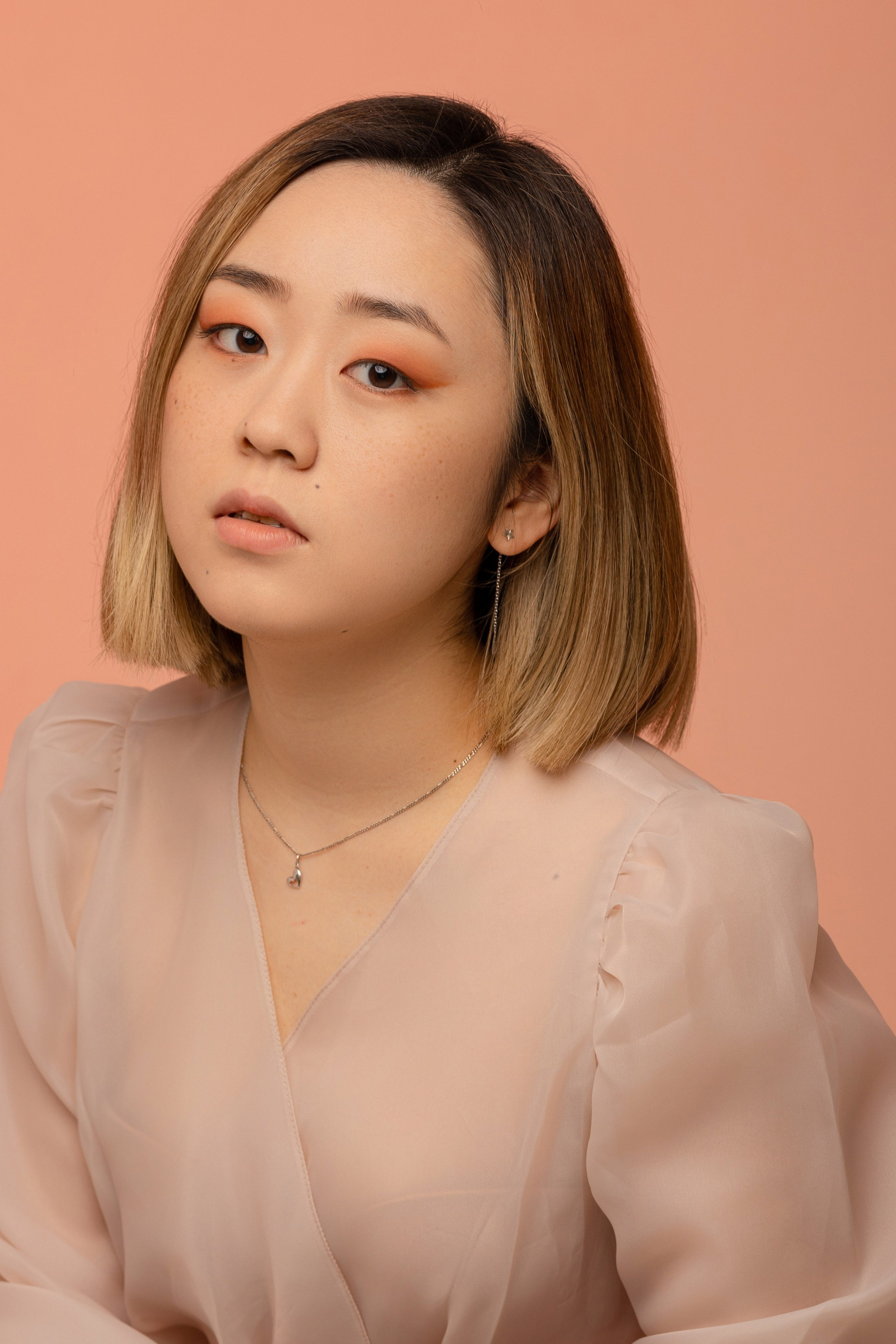 Девушка крупным планом, с приподнятым подбородком на розовом фоне.