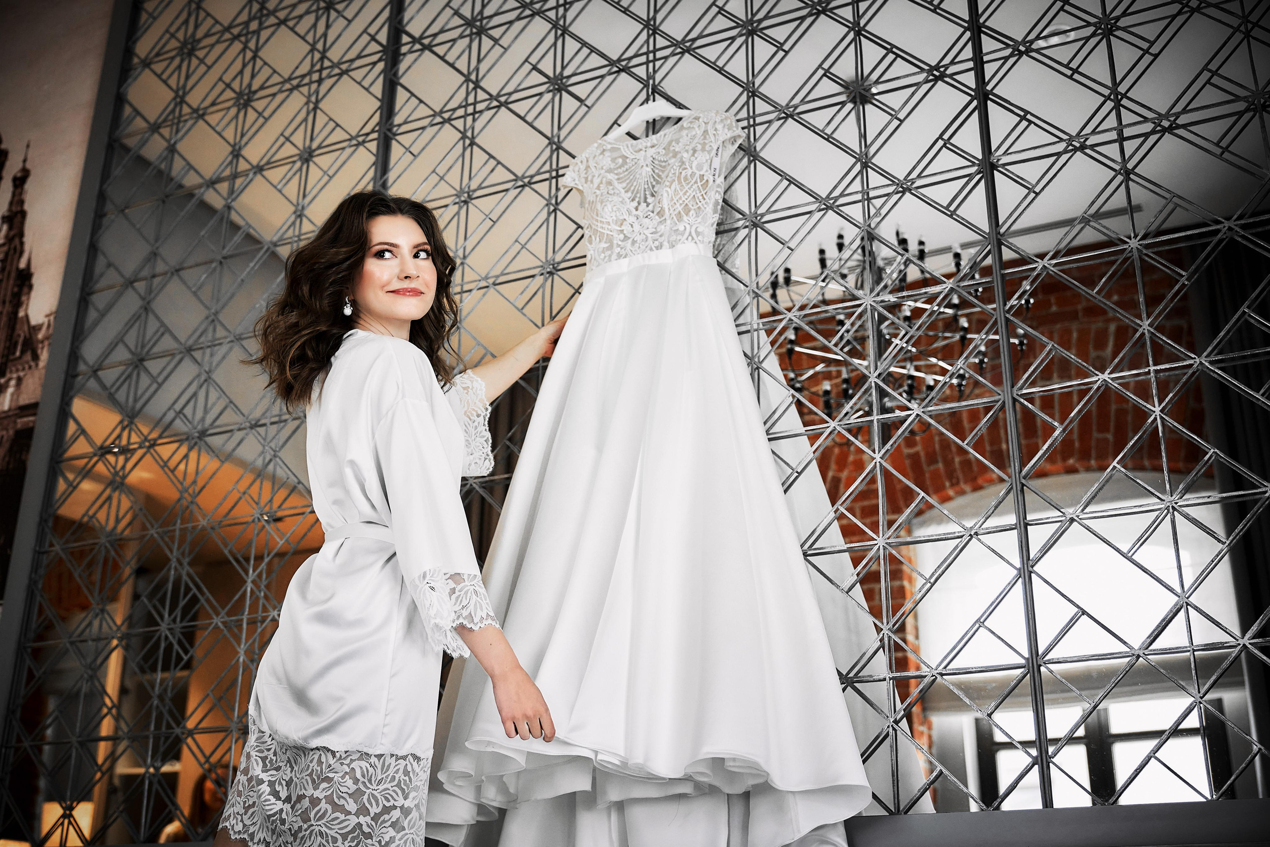 невеста держит свадебное платье, номер в отеле для сборов невесты