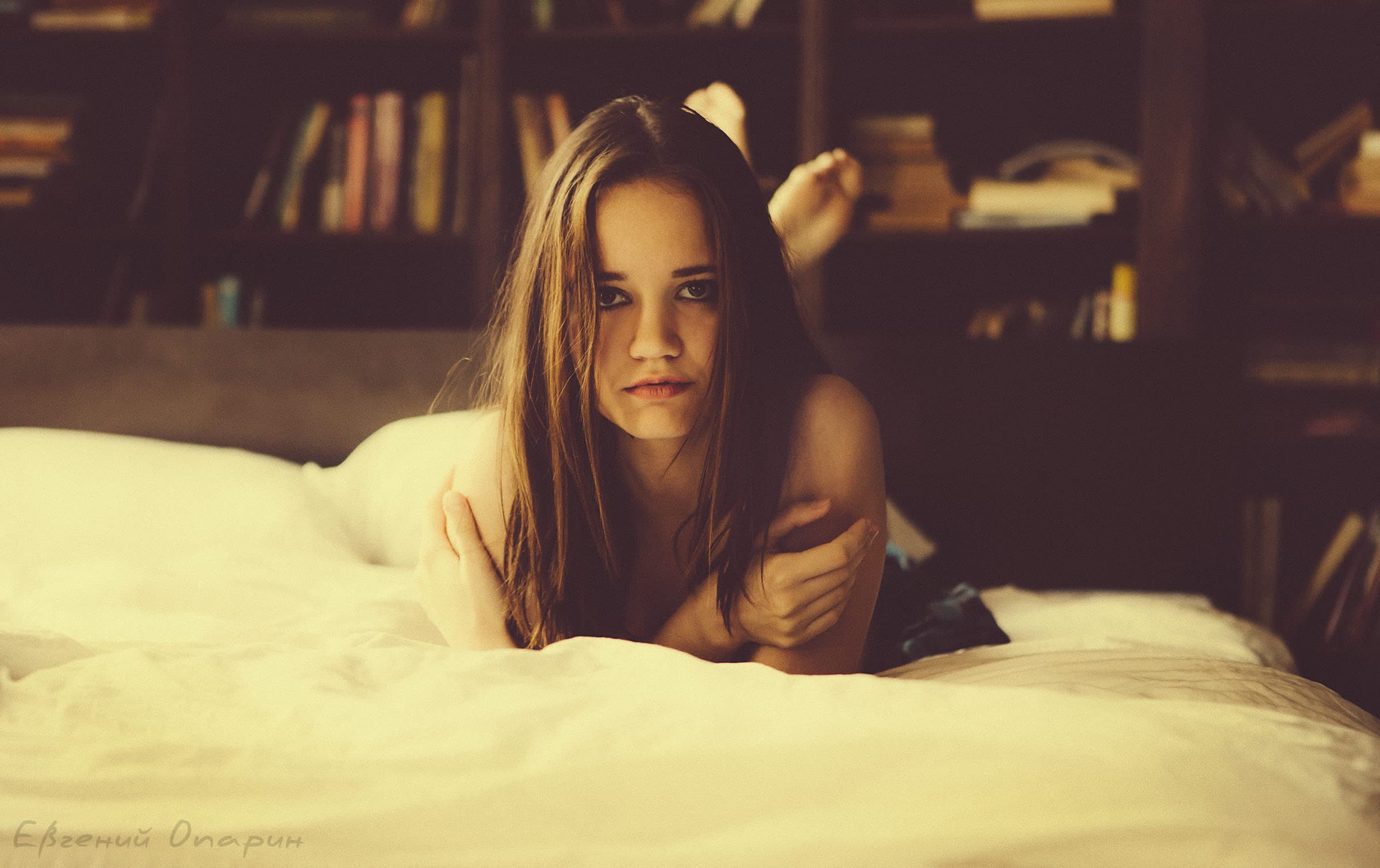 девушка на кровати у книжного стеллажа 