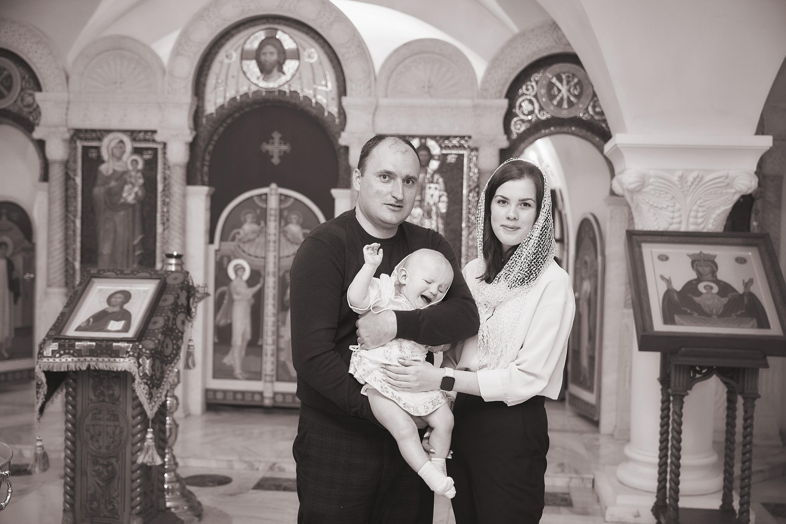 крёстные родители держат ребёнка в церкви после крещения