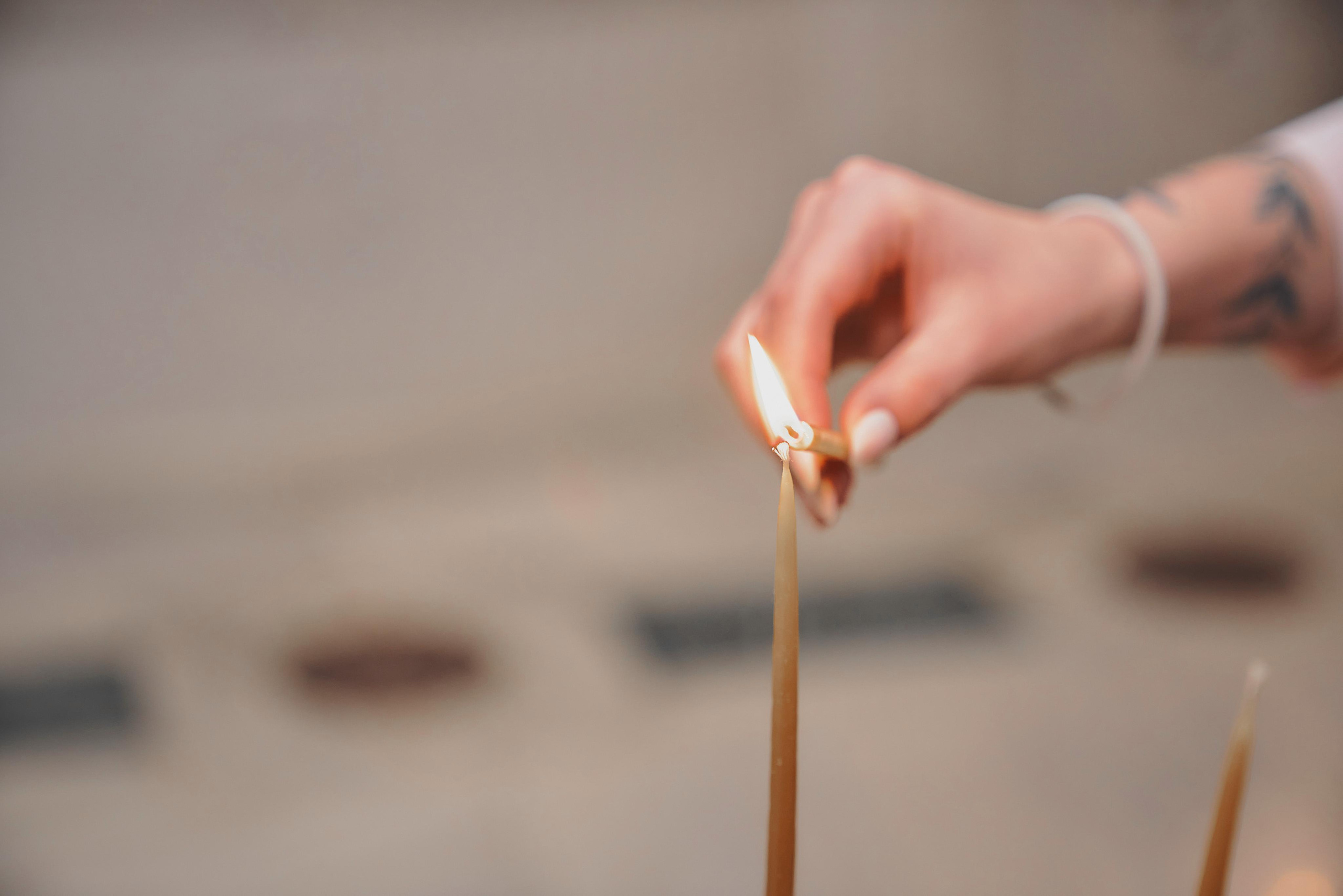 крупный план руки зажигающий свечу в храме