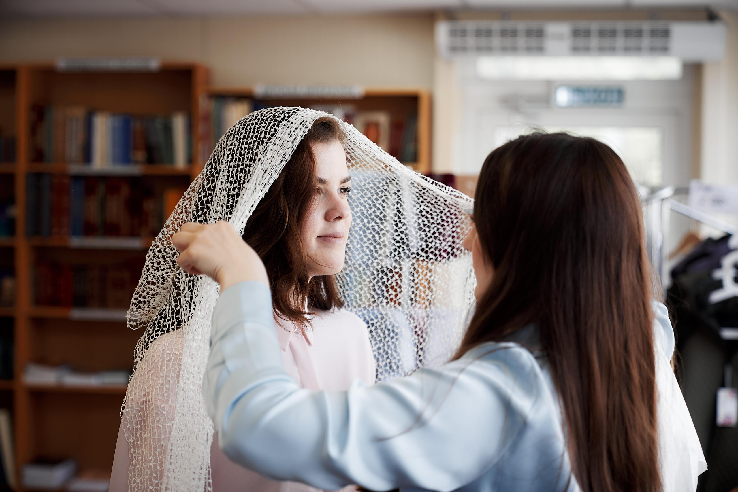девушка одевает платок в церкви перед крещением
