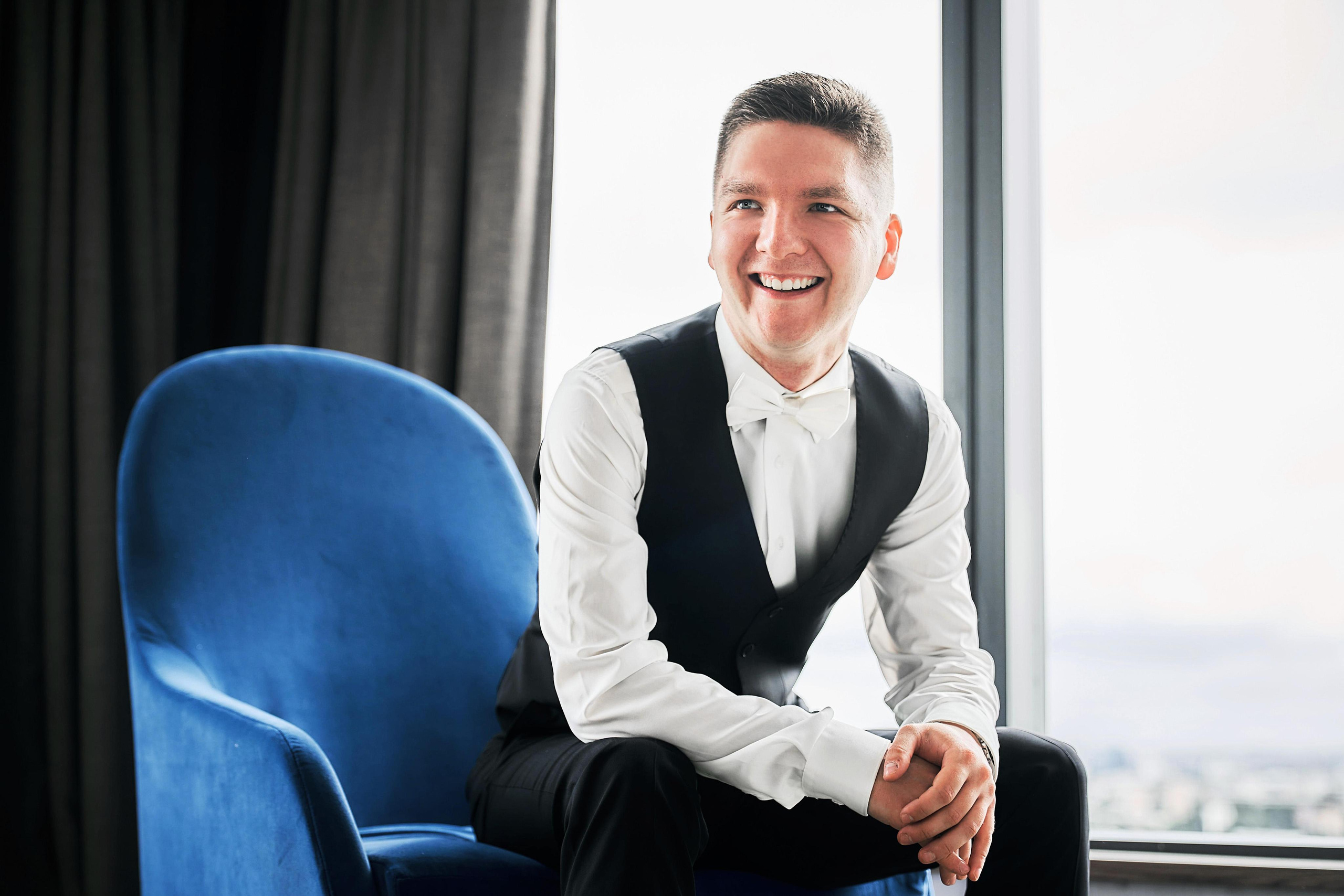 жених сидит на синем кресле номере отеля Radisson Blu