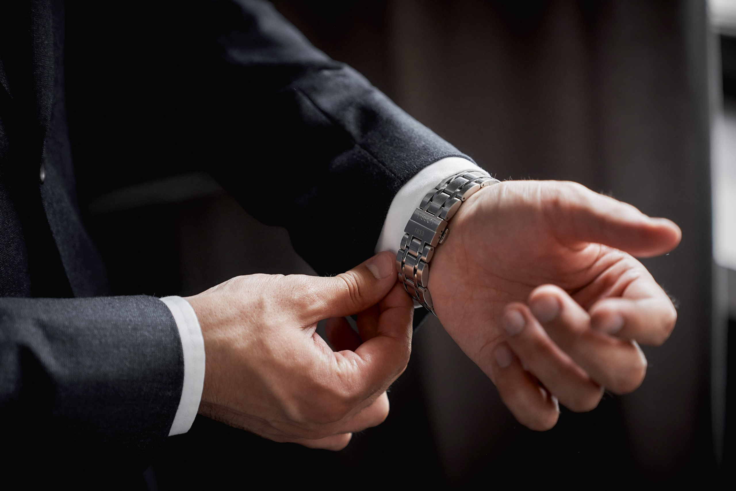 крупно мужские руки застёгивают браслет часов