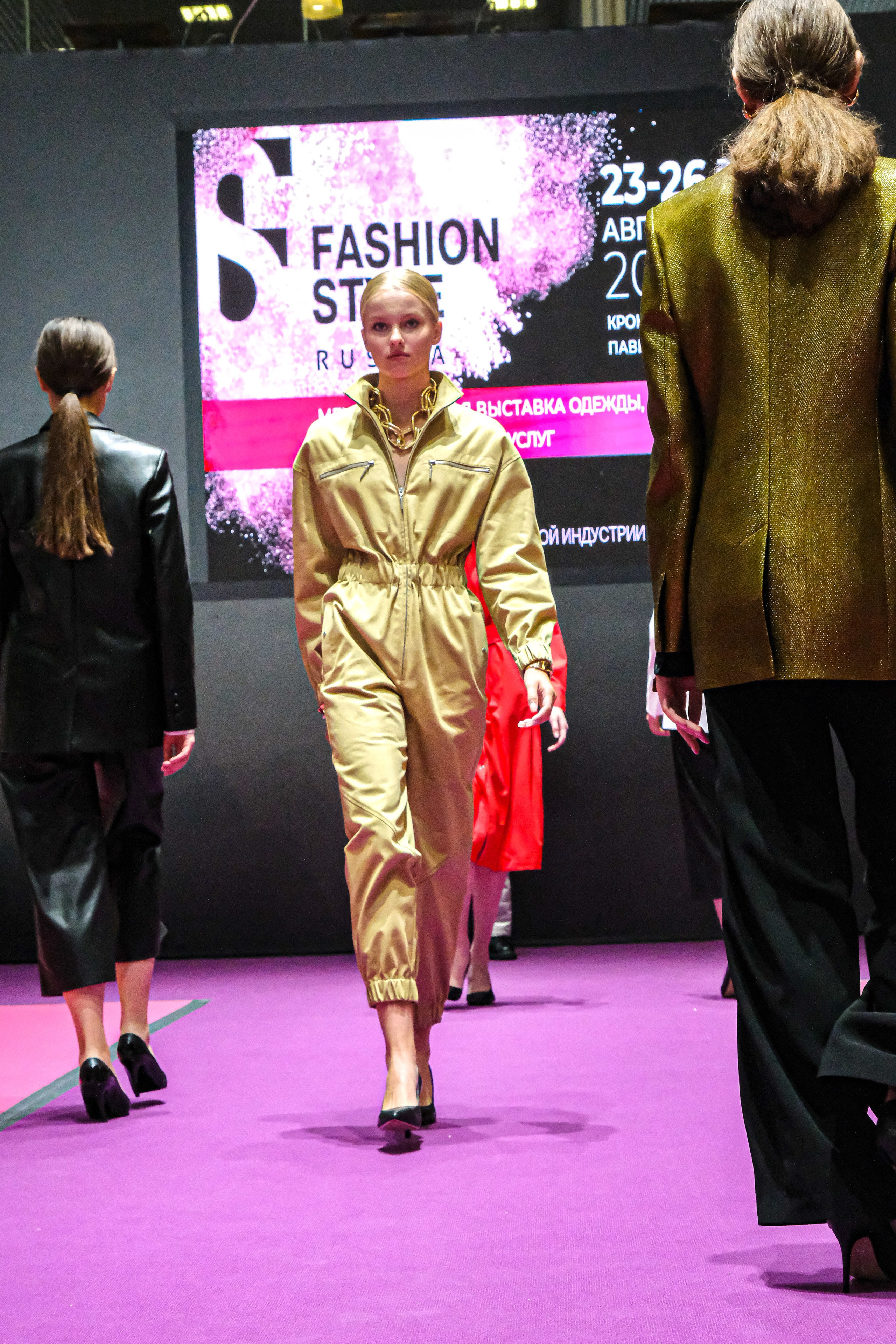  "Модели в ярких нарядах проходят по подиуму во время показа мод, освещенные яркими софитами и окруженные восторженными зрителями."