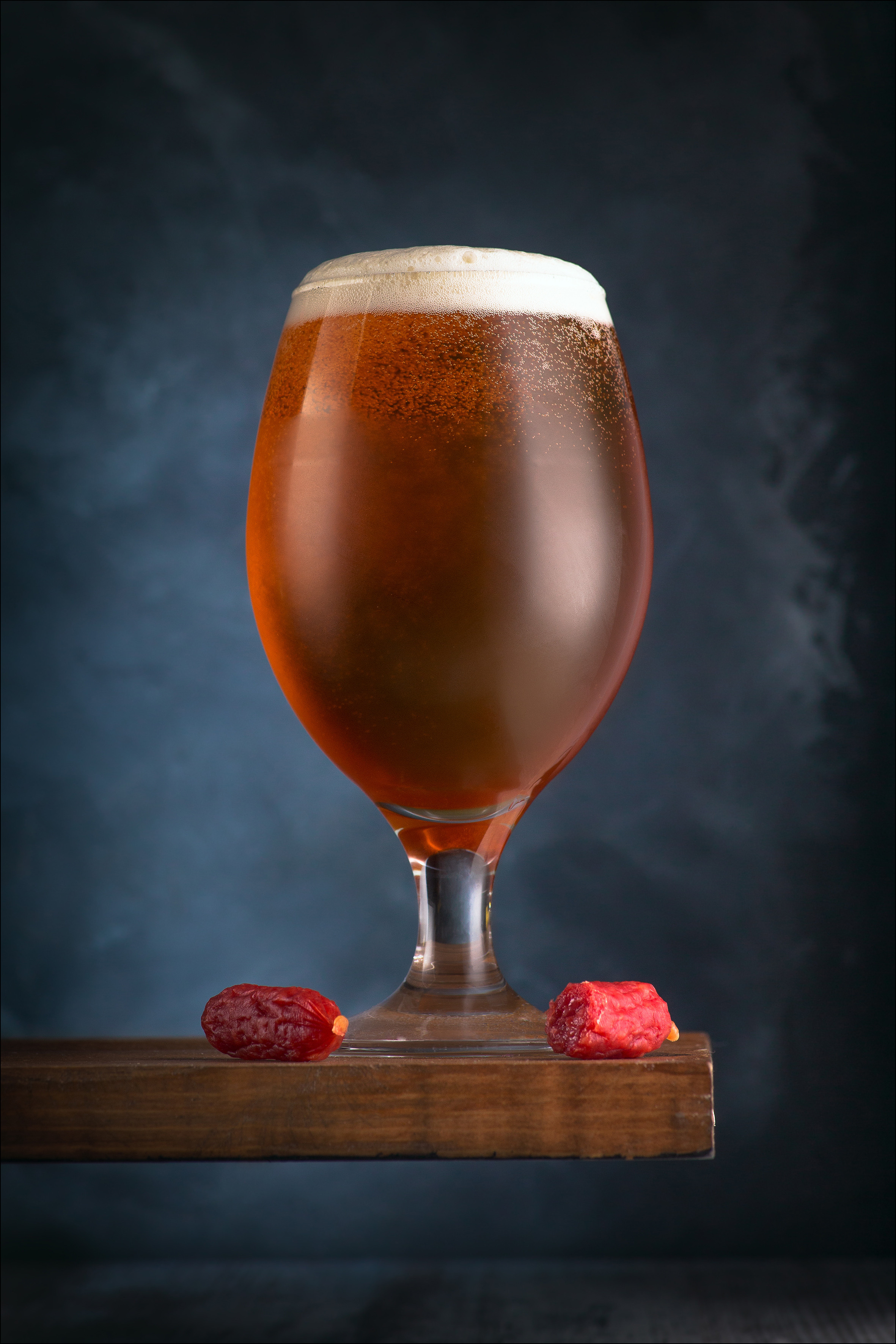 Ароматное тёмное пиво в стеклянном бокале с пенкой