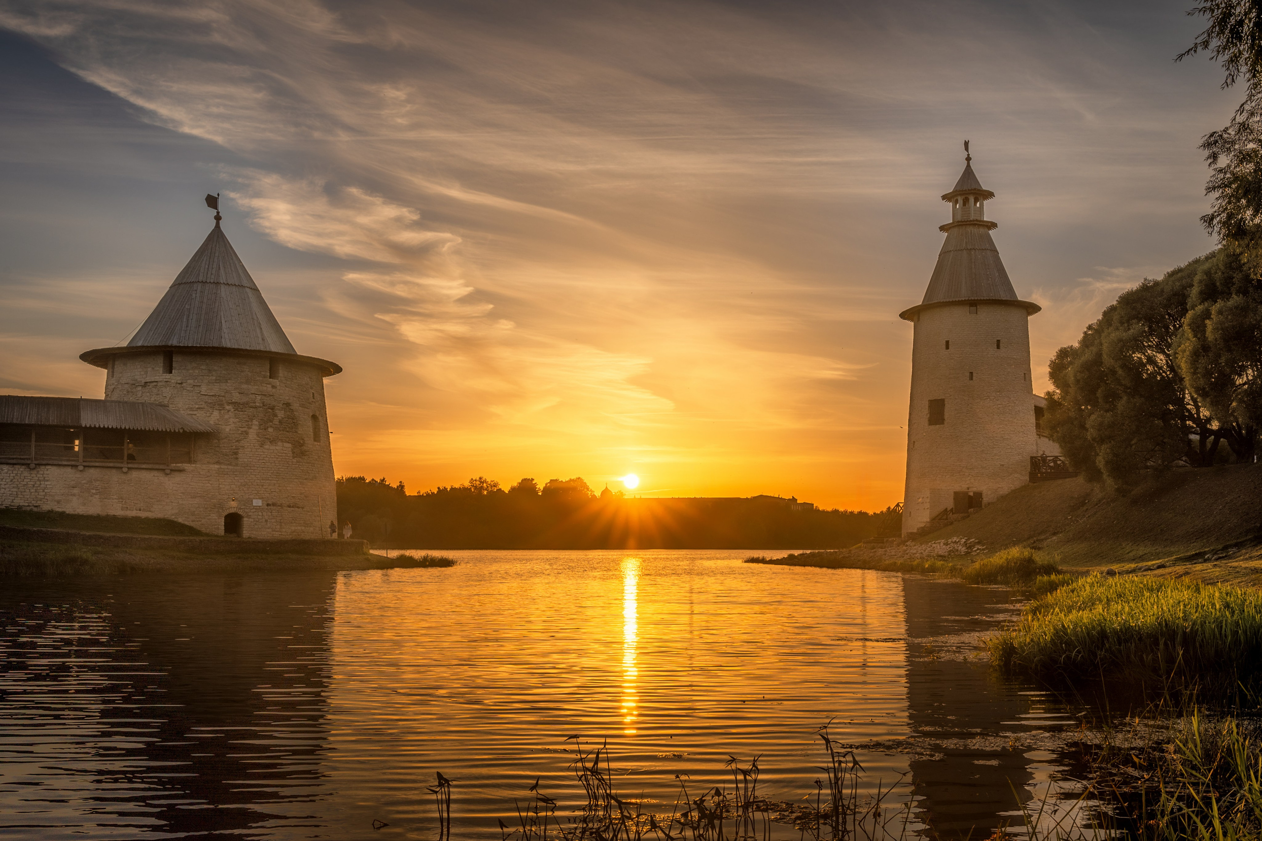 Две башни Псковского кремля на фоне закатного солнца