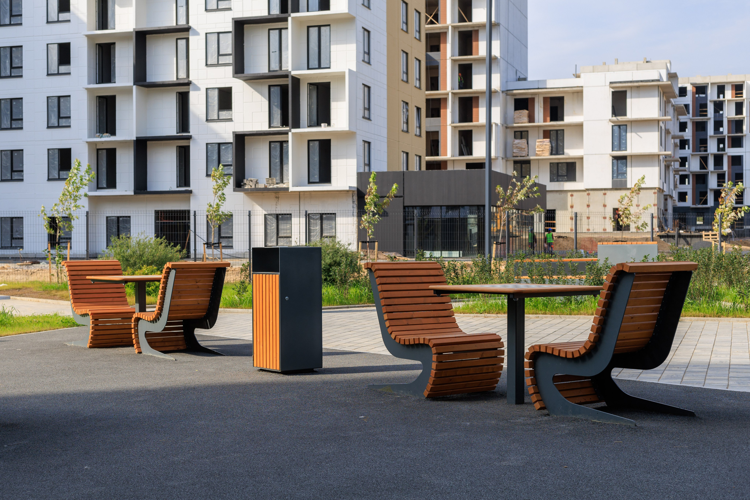 Зона для игры в настольные игры - несколько столов с шахматной разметкой и креслами по бокам. На фоне - многоэтажные современные дома.