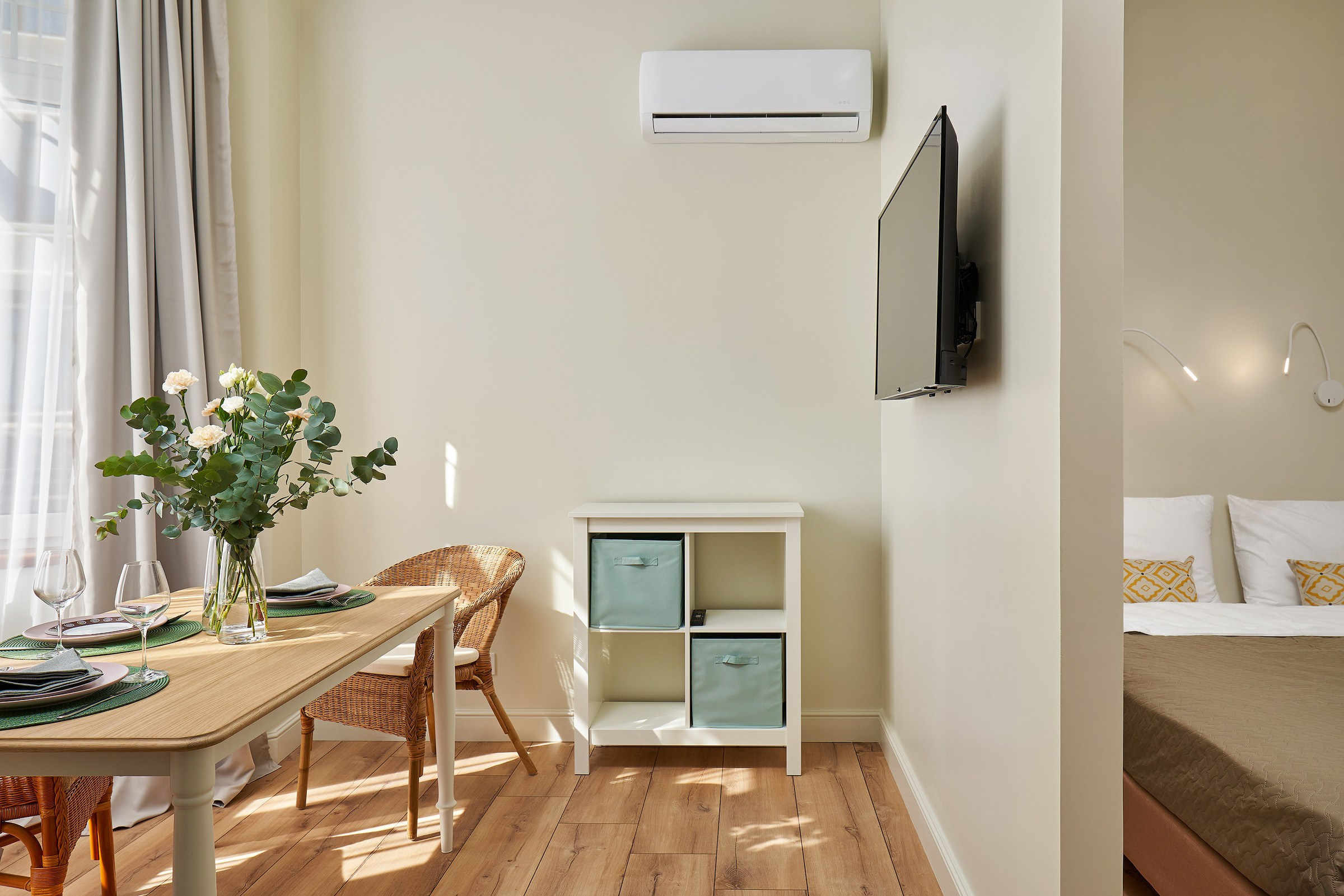 Гостиная-столовая, деревянный стол, цветы, бокалы. Солнечный свет.