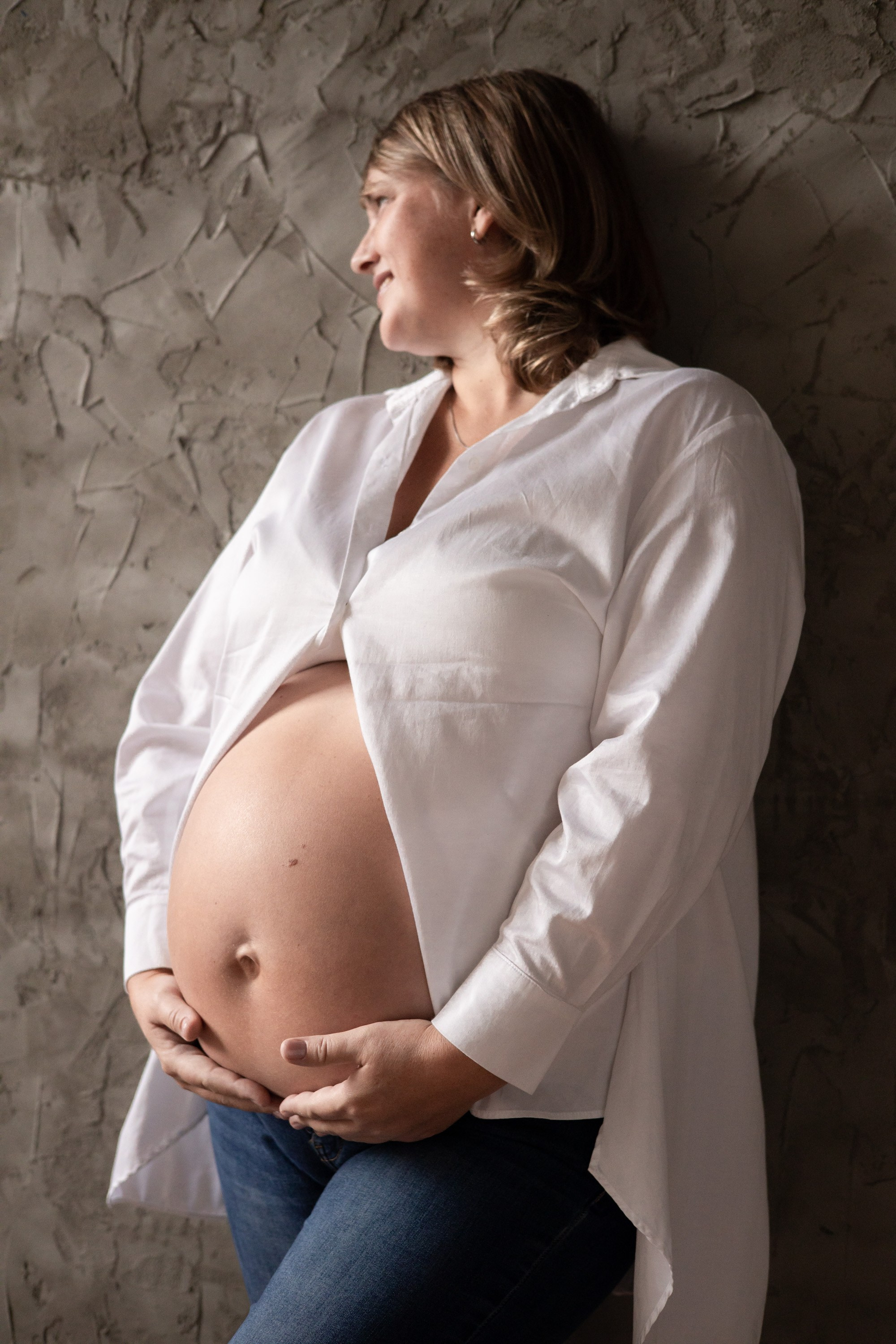 Беременная женщина стоит у стены. Фотосессия для беременных Астрахань.