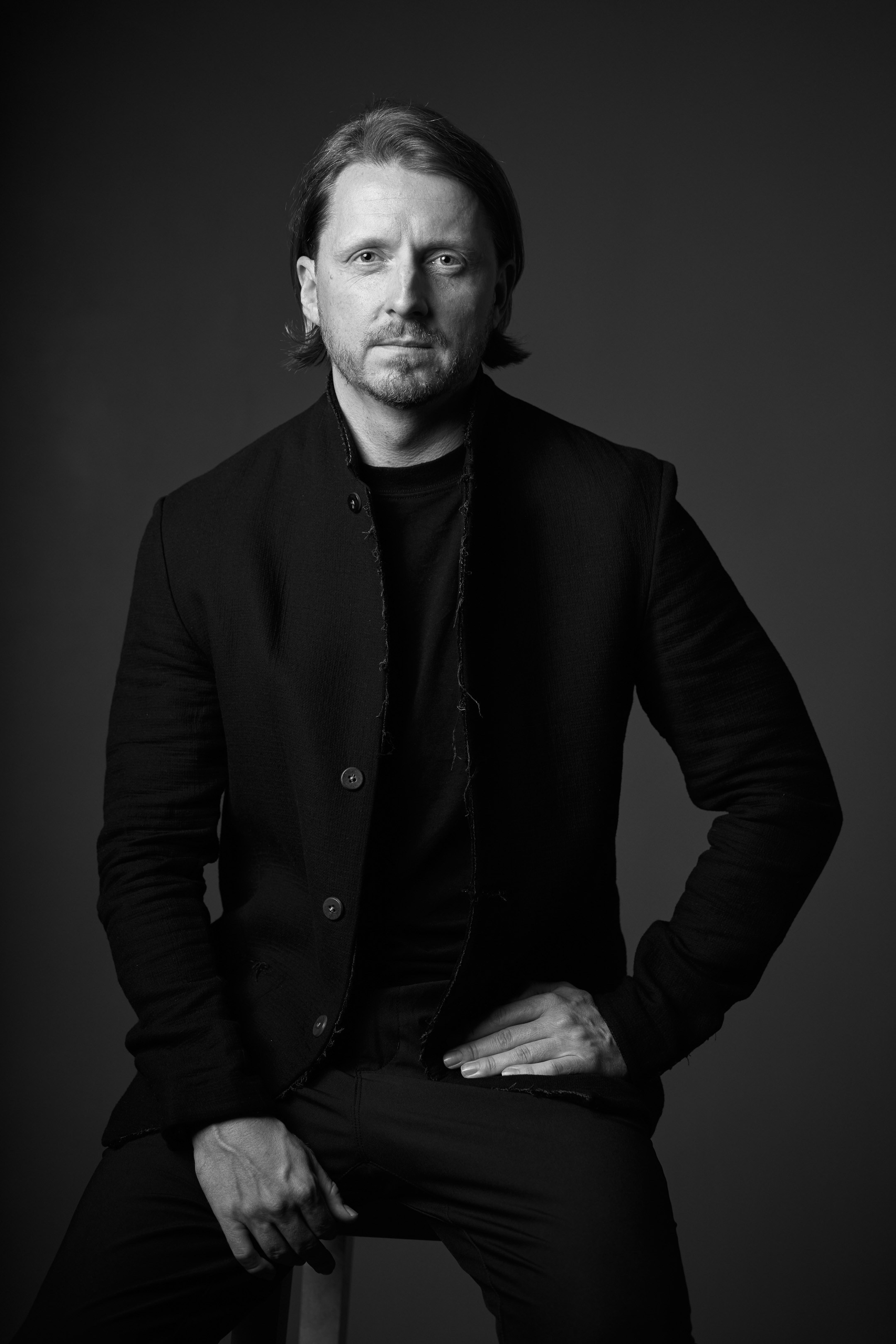 Black and white business portrait of a confident man in a suit on a black background