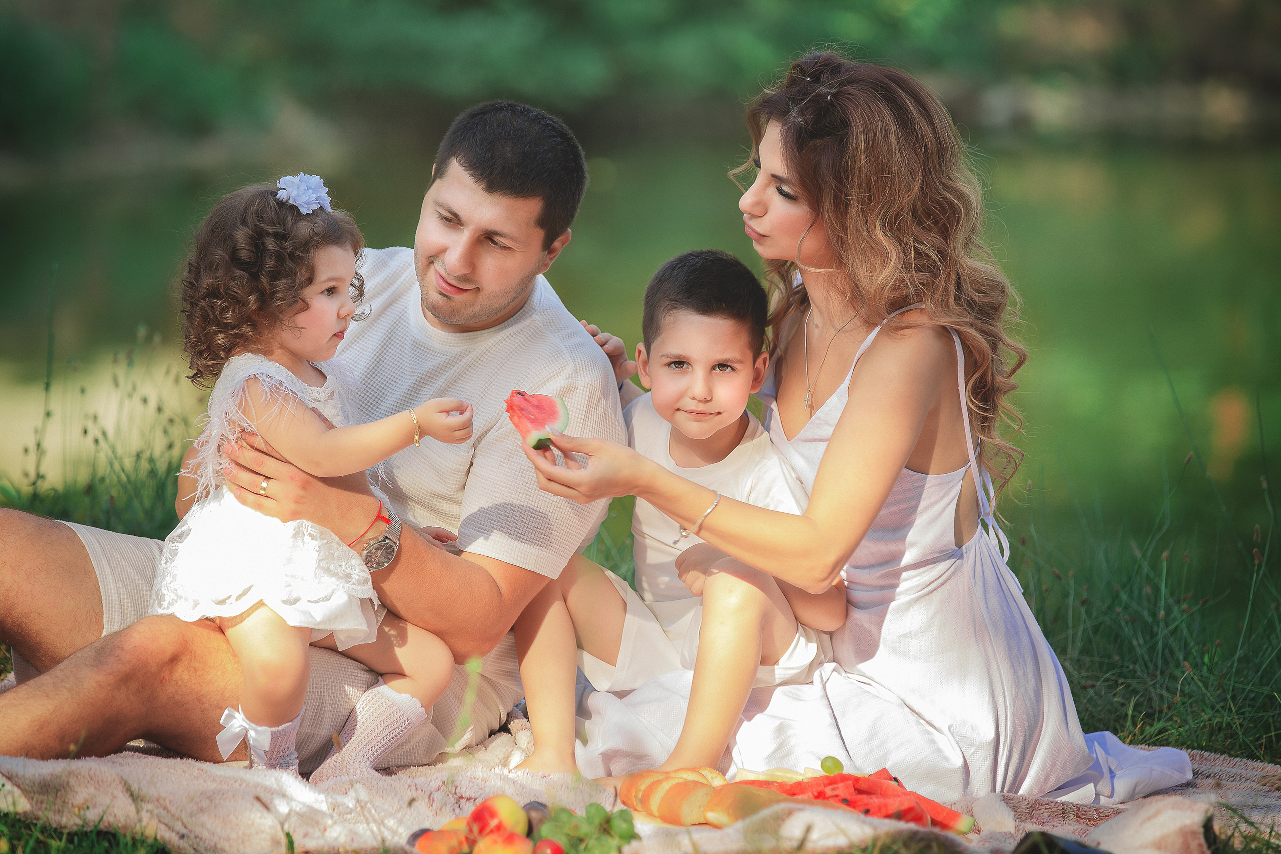 Счастливая молодая семья с детками собрались на пикнике возле озера