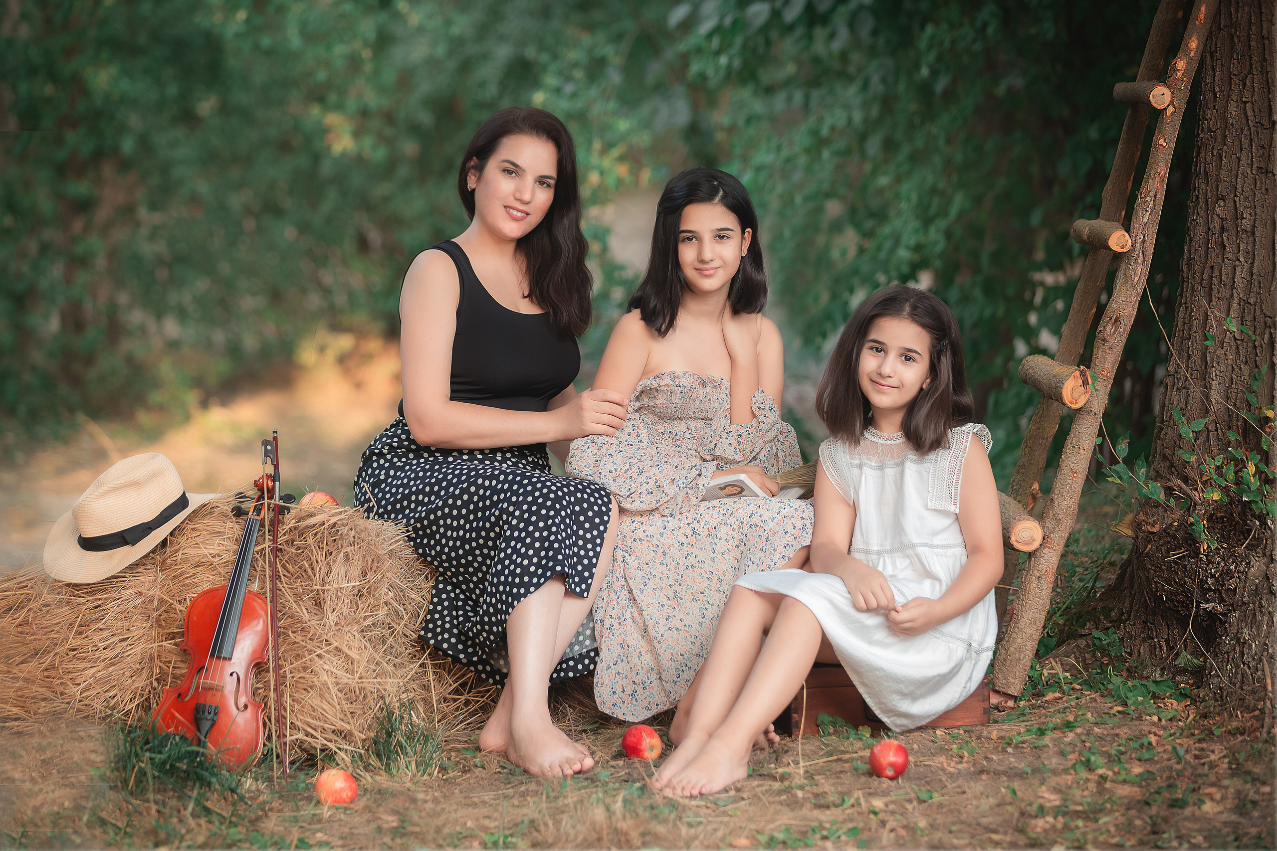 Мама с дочками возле дерева, стоит лестница из срубов, рядом лежит скрипка