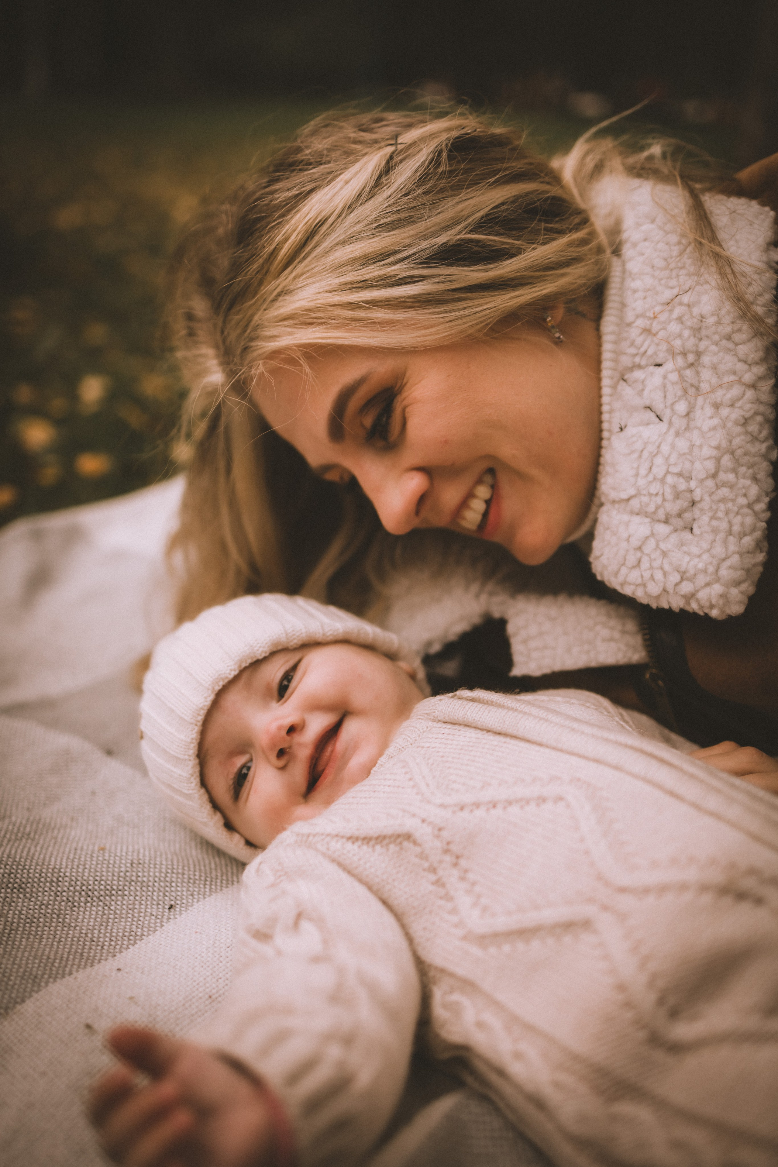 Дочка улыбчиво тянется к маме, лежит на одеяле