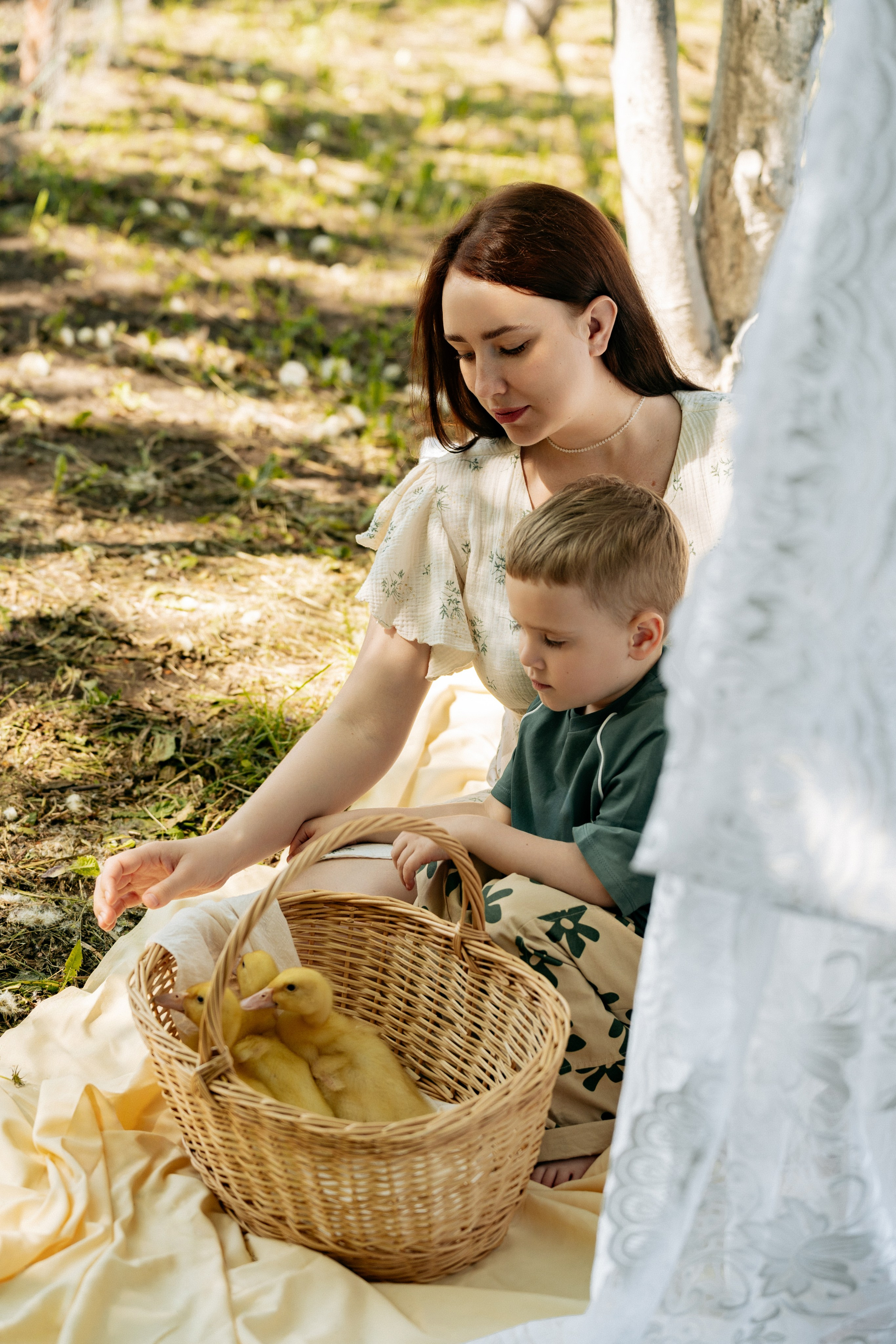 Мама и сын сидят на траве, утята в корзинке выглядывают, солнце освещает кадр, фотограф Геленджик