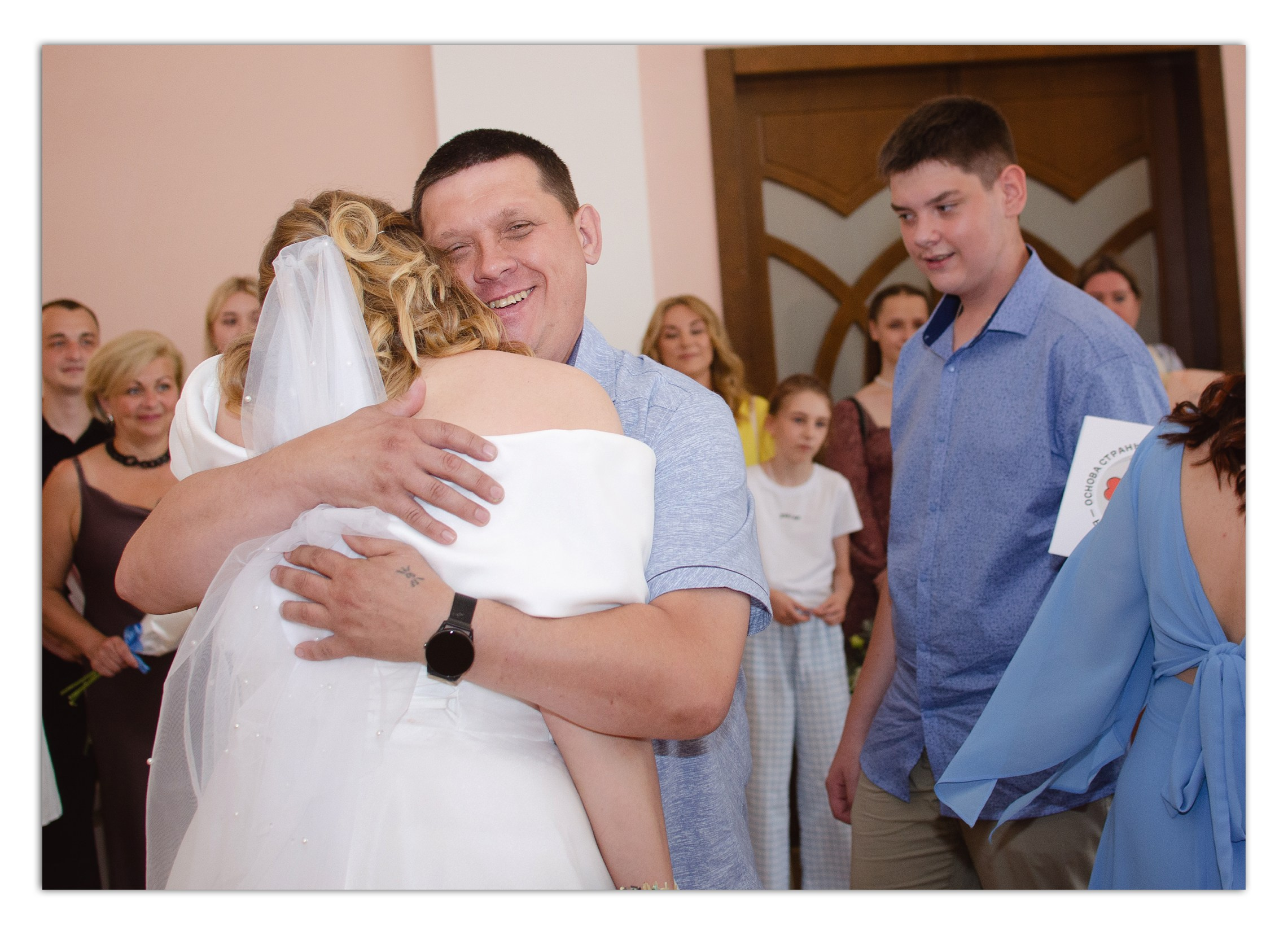 Репортажная фотосъемка свадьбы в ЗАГСе - трогательная свадебная сцена: невеста обнимает гостя в зале