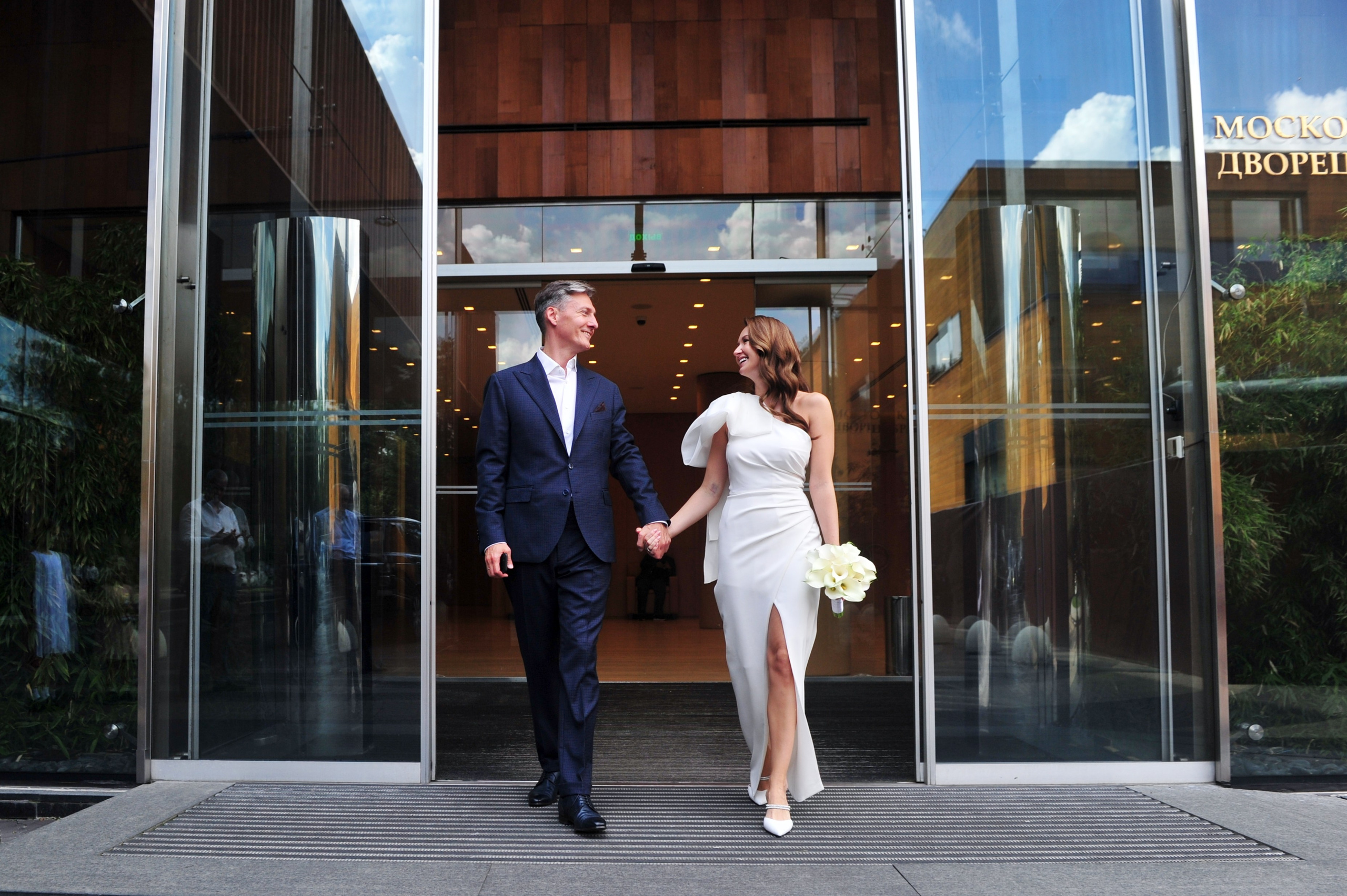 Свадьба в ЗАГСе Барвиха Luxury Village летом, жених и невеста выходят из ЗАГСа